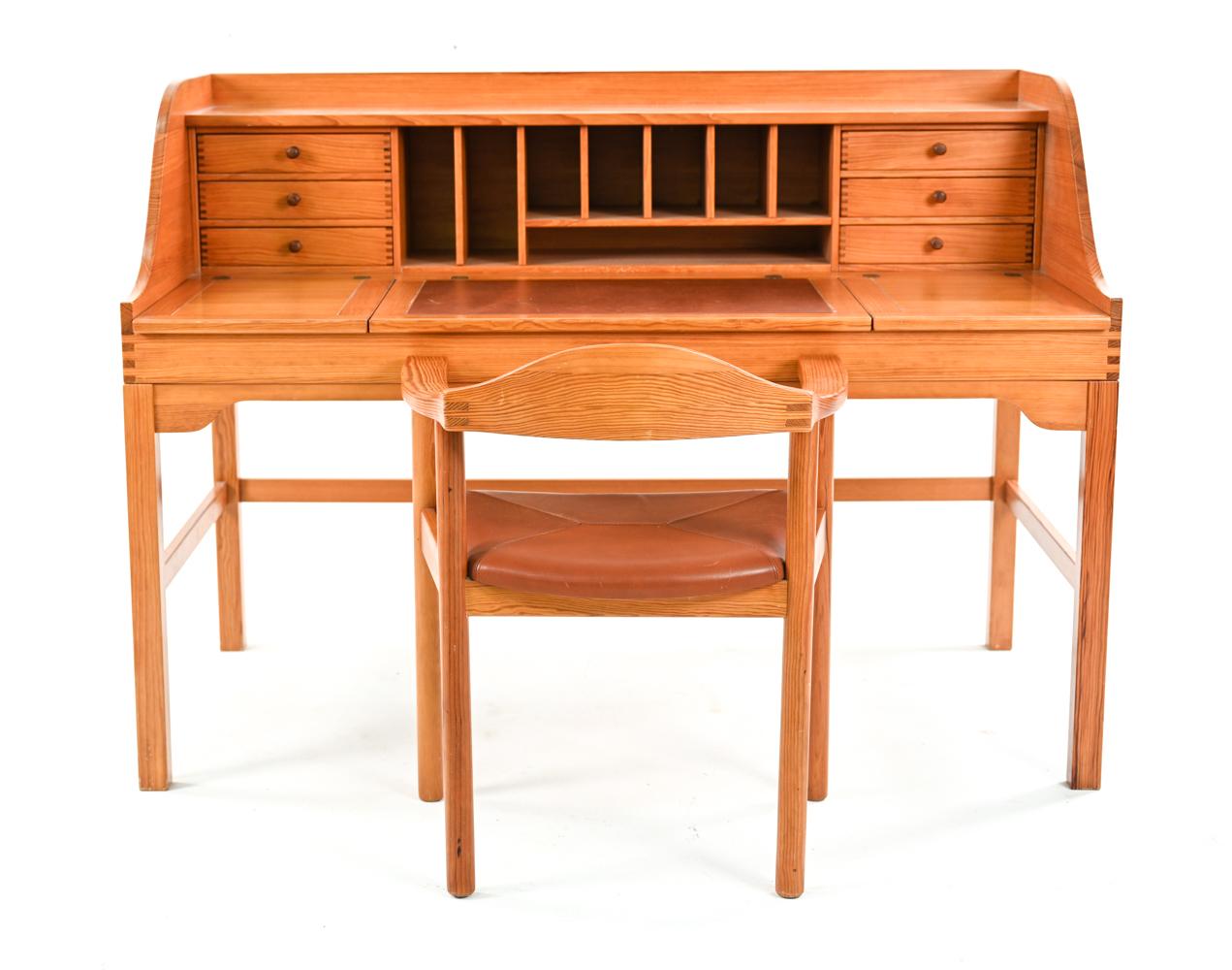 A Mid-Century Modern free-standing desk made of pine, designed by Andreas Hansen. Featuring top with three flip up leaves, under which storage compartments, middle section with brick-red leather writing blot, six drawers and compartments, finished