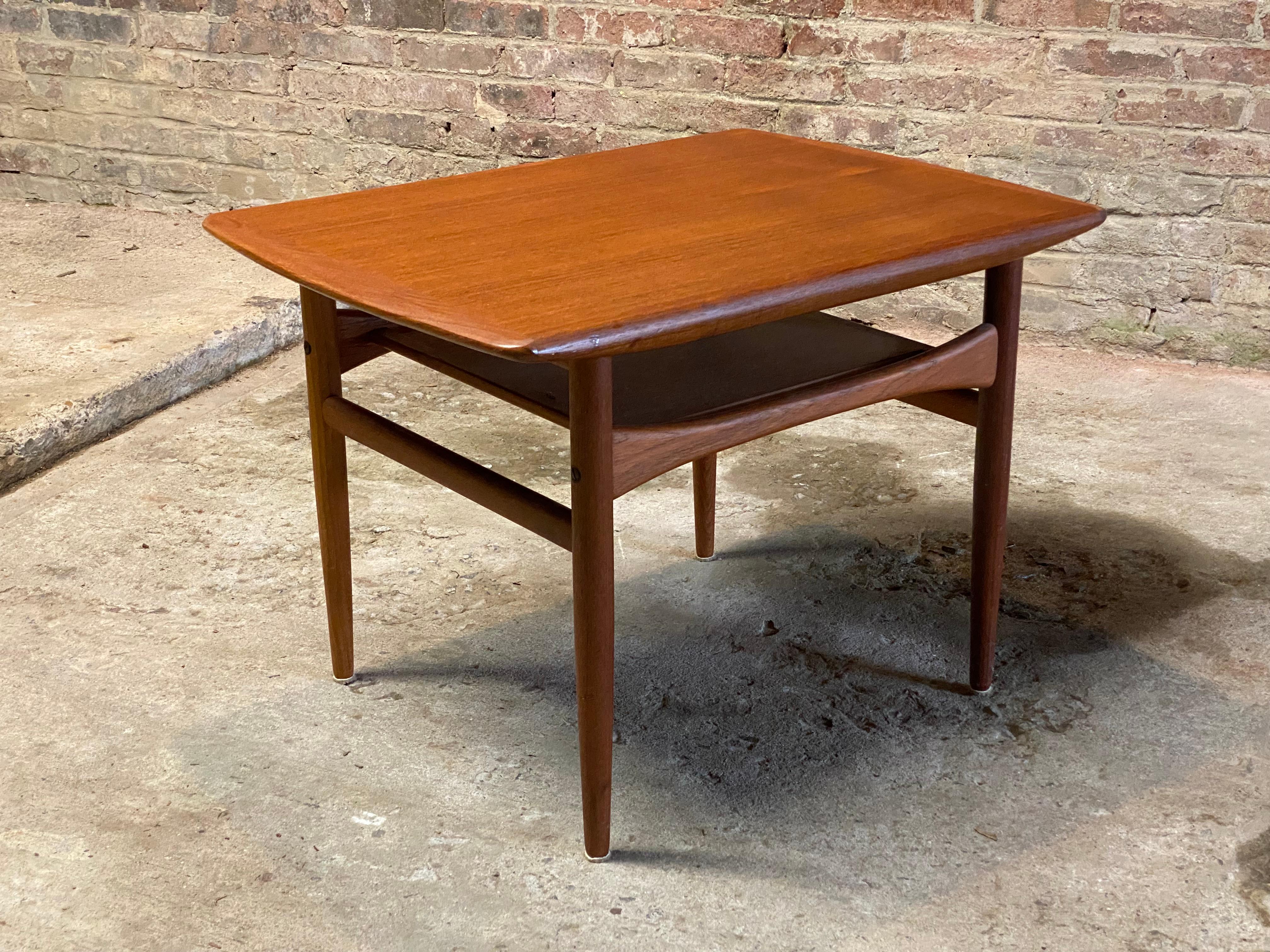Danish Modern teak coffee table designed by Andreas Hansen for Arrebo Mobler. The table features nicely tapered legs, figured top board veneers, arched center stretchers with a lower shelf. Circa 1960-70. No marks, labels, medallions or