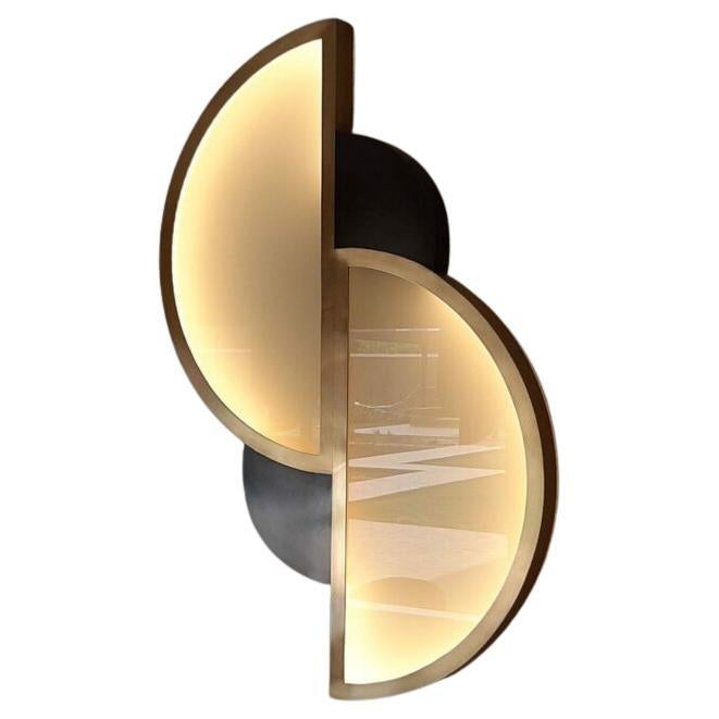 L'applique Andrée 1 presenta una composizione geometrica verticale che combina forme a semicerchio e a quarto di cerchio in una disposizione accuratamente bilanciata. Due pannelli in vetro smerigliato, incorniciati in ottone patinato oro