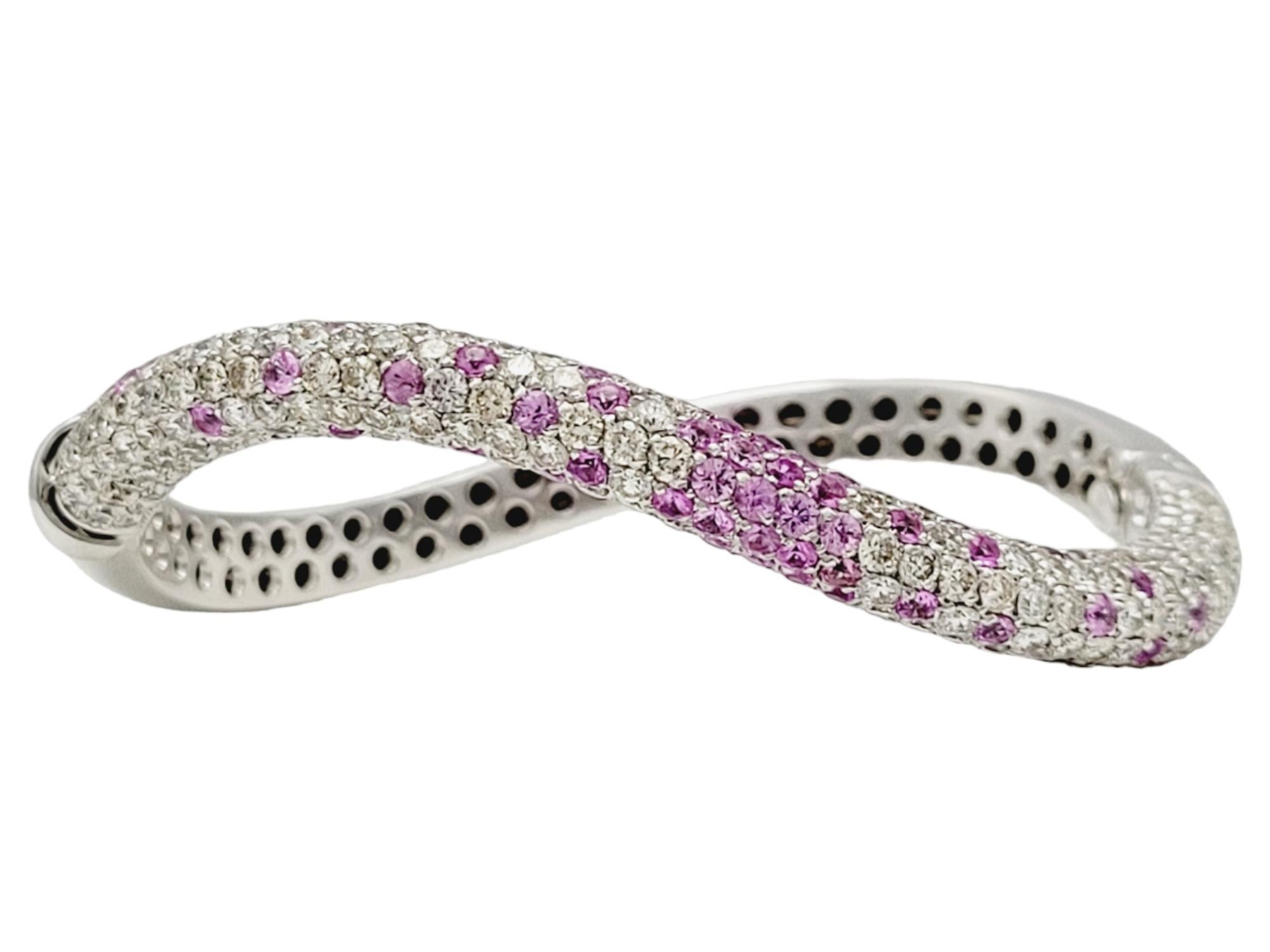 This is a gorgeous, ultra feminine diamond and pink sapphire bangle bracelet. Contemporary in style, the sleek curved design is enhanced by the colorful sprinkling of pink sapphires against the icy white diamonds. An absolutely lovely piece!

This
