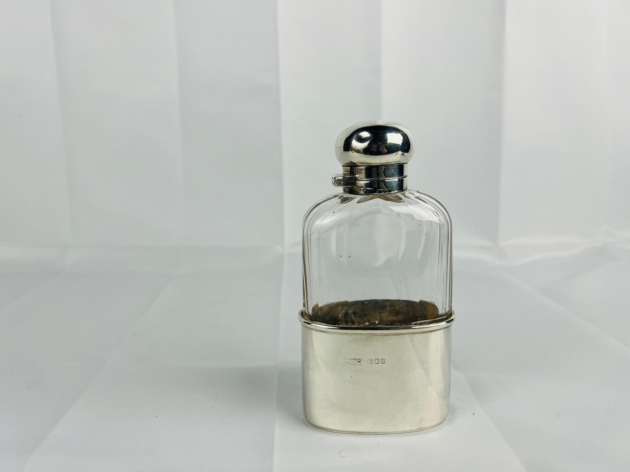 Diese seltene Verschlussflasche aus Sterlingsilber und Glas, die von Andrew Barrett & Sons hergestellt wurde, ist ein Beispiel für den britischen Einfallsreichtum und die Handwerkskunst des frühen 20. Der Flachmann besteht aus mundgeblasenem Glas