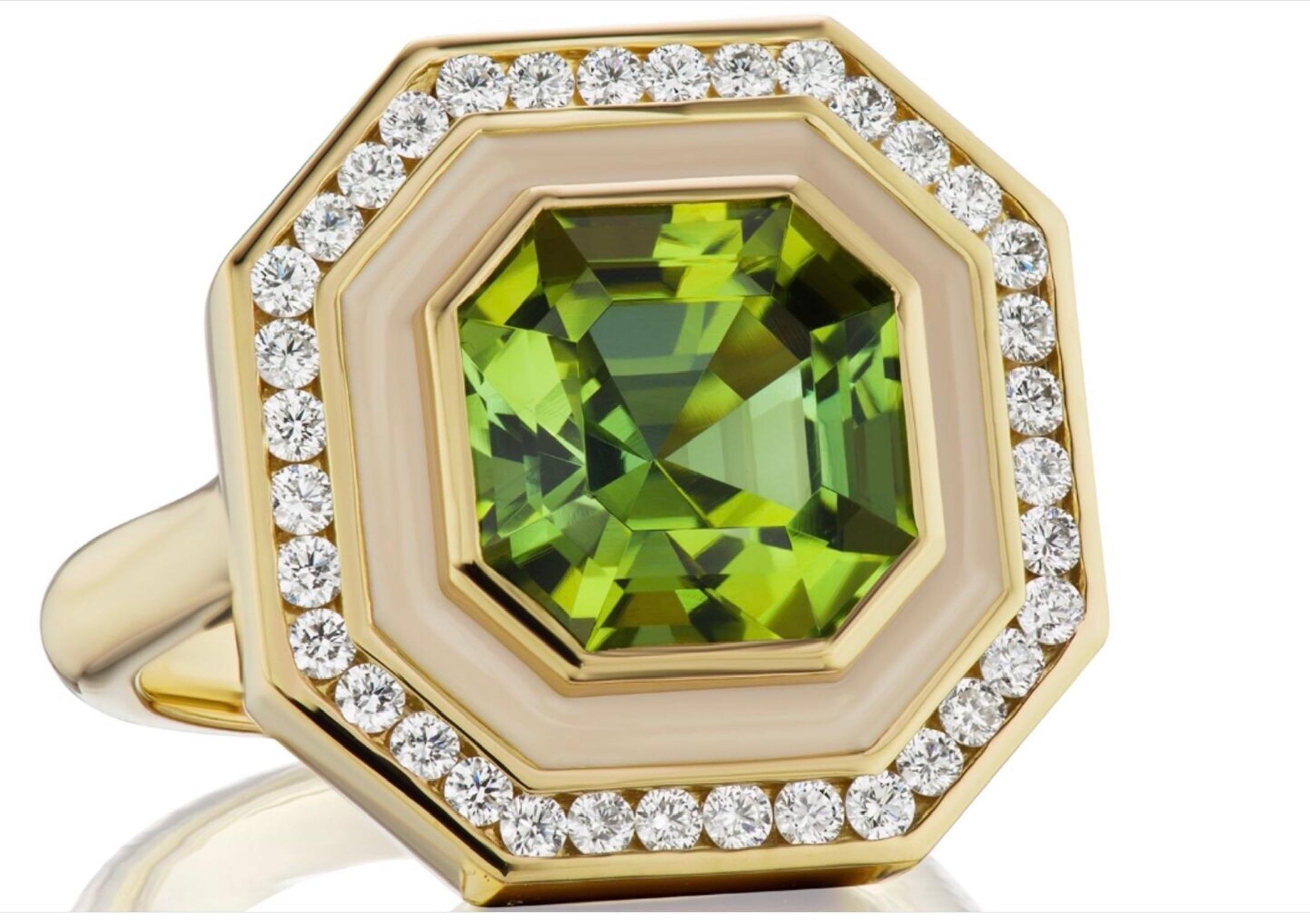 A sparkling, eye-clean, 5 carat Asscher cut Green Tourmaline. It is a mesmerizing stone that has been set and surrounded by .50 ctw of GH VSI Diamonds, followed by a border of cream colored enamel. This ring is set in 18K Yellow Gold and is a size