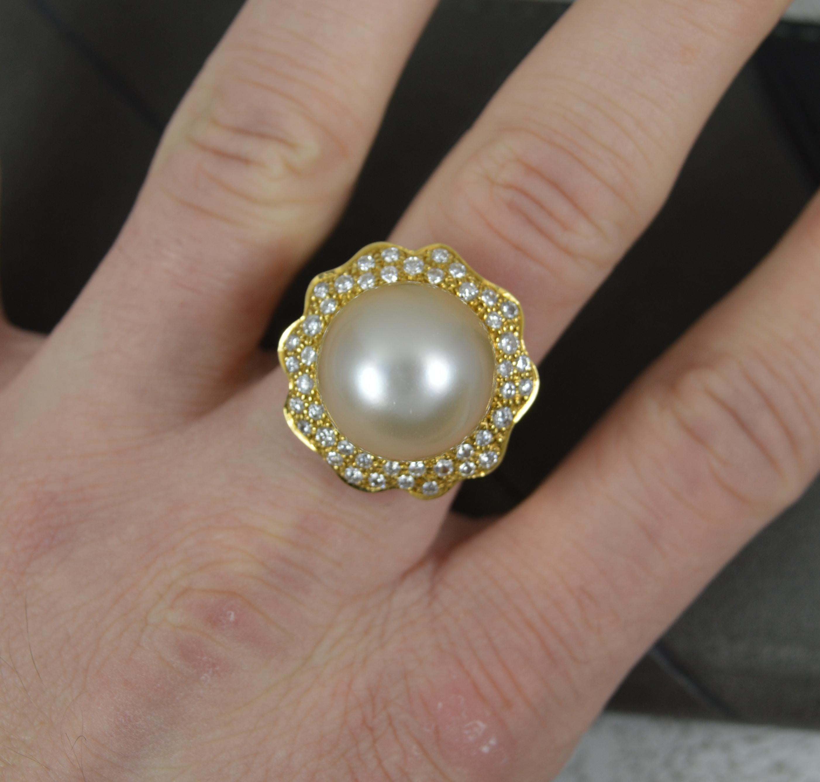 A stunning pearl and diamond ring by the renowned maker Andrew Grima.
Solid 18 carat yellow gold example. Heavy and solid.
Designed with a large pearl to centre, 14mm diameter. Surrounding are many round brilliant cut natural diamonds forming a