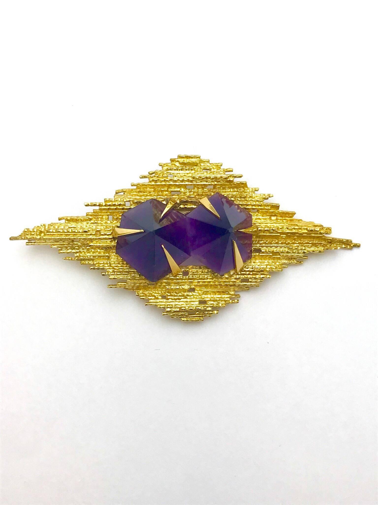 An Andrew Grima amethyst and 18 karat yellow gold pendant brooch. created in the fashion of many of his pieces, the two conical cut amethyst have a total weight of 45.80 carats, set with large pointed prongs, in a textured yellow gold frame.  The
