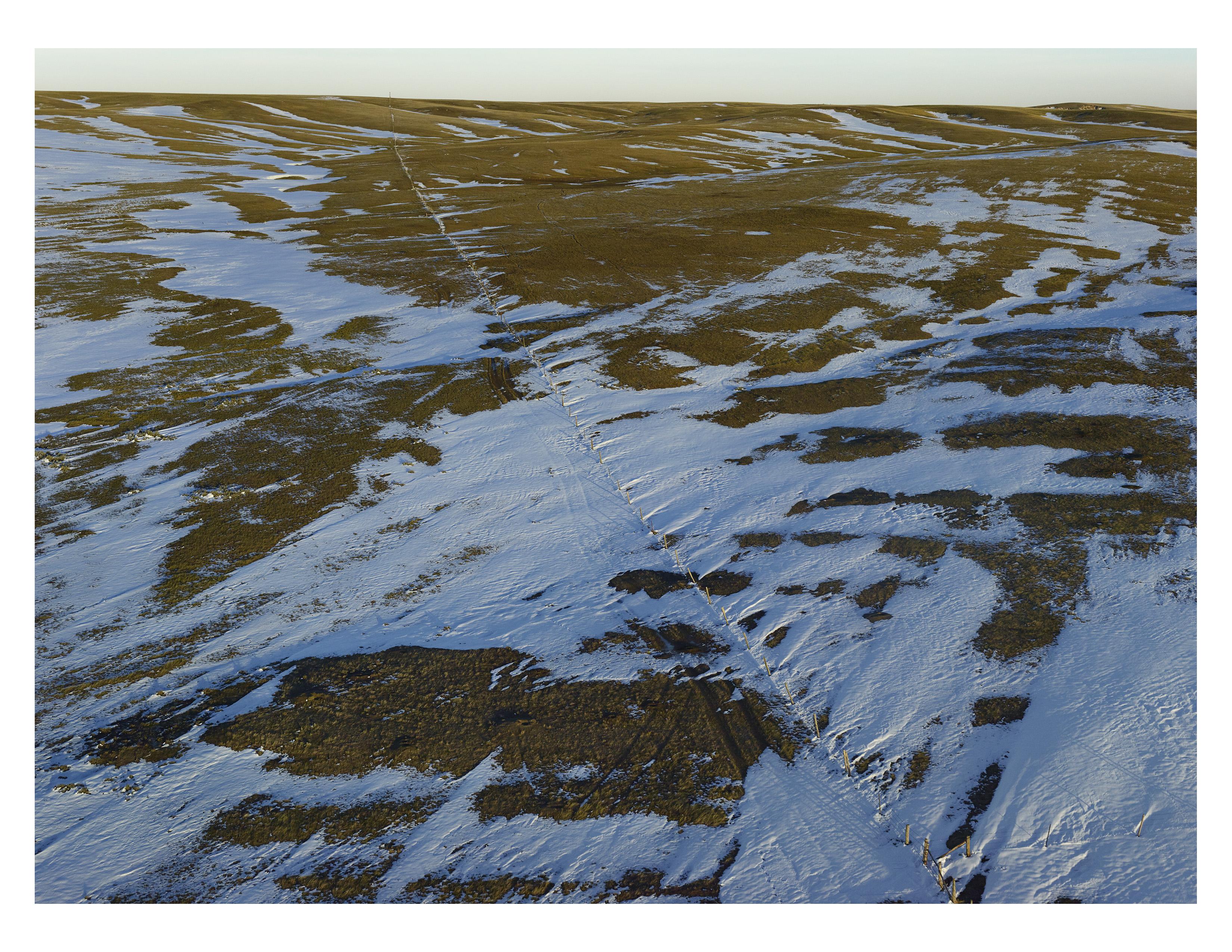 Archival Pigment Print

The landscape shows traces of a famous early-October blizzard that killed tens of thousands of cattle. Still in their unprotected summer pastures, they ended up crammed against the fence lines and suffocated in the snow. In