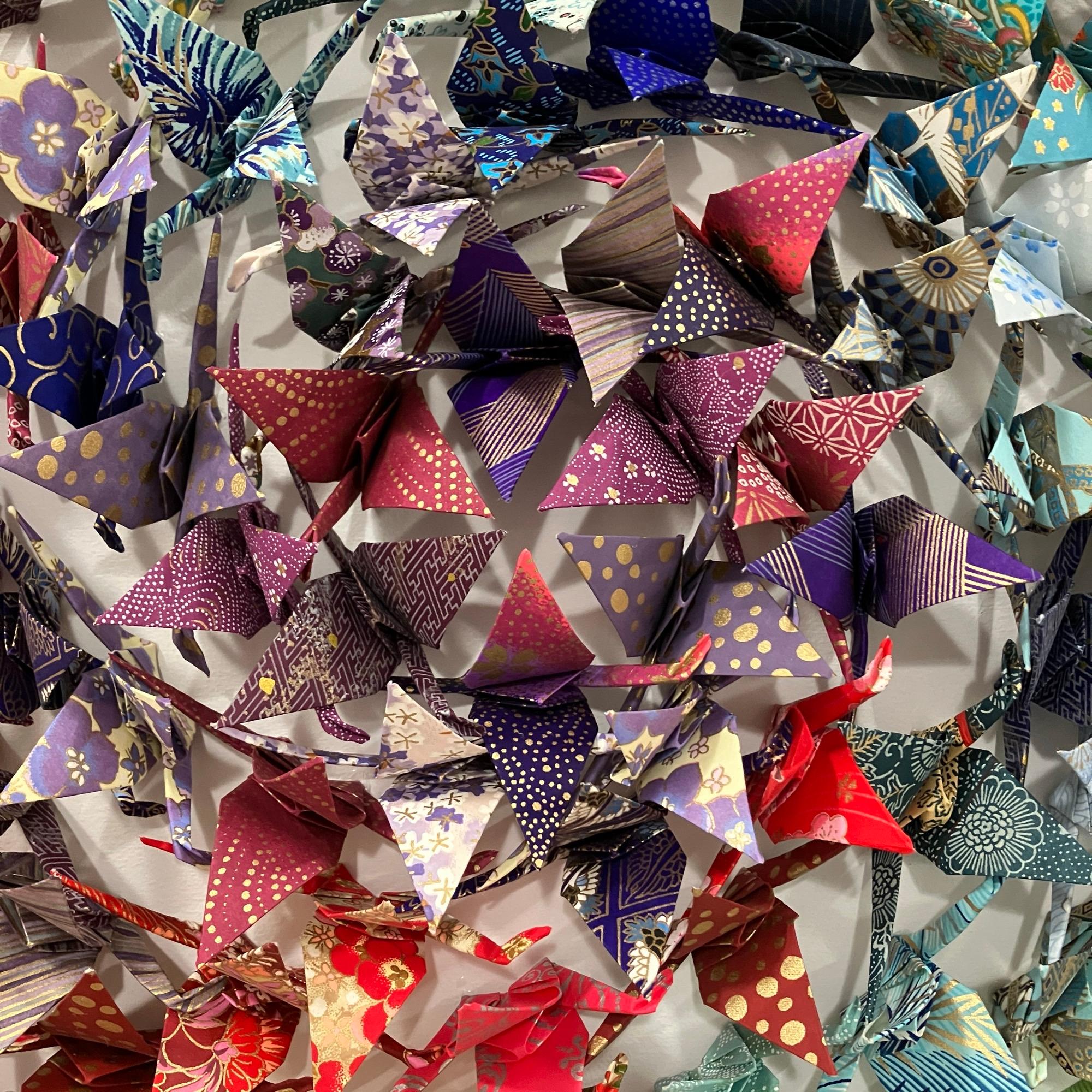 Dieses einzigartige Origami-Werk zeigt Hunderte von handgefalteten Chiyogami-Papierkranichen, die präzise auf eine Holzplatte montiert und in eine elegante Acryl-Schattenbox gerahmt sind.

Andrew Wang erkundet große Reisen durch Origami-Assemblage,