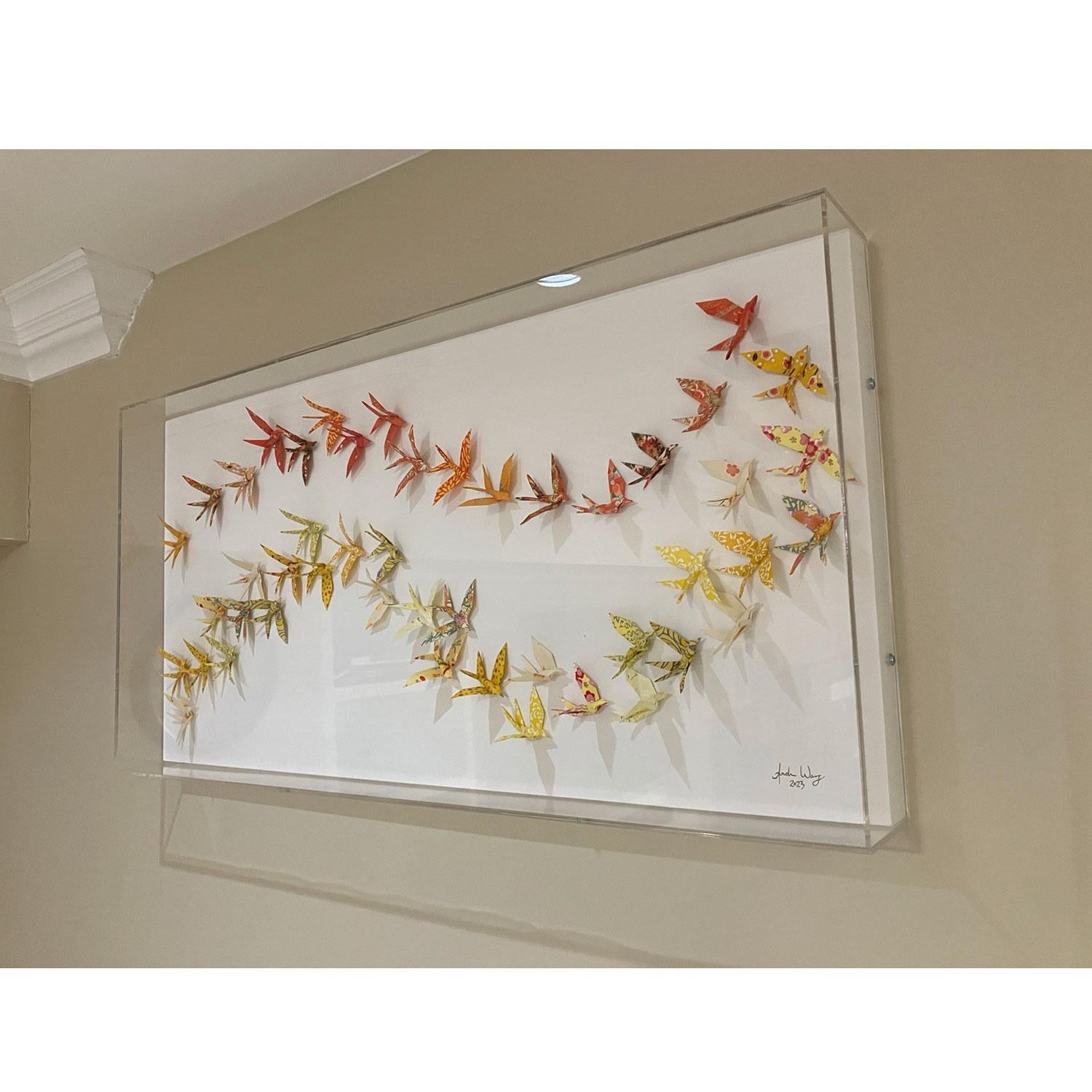 This unique origami piece features hundreds of hand folded chiyogami paper birds mounted precisely on wood panel and framed in an elegant acrylic shadow box.

Andrew Wang unearths great journeys through origami assemblage, influenced by his