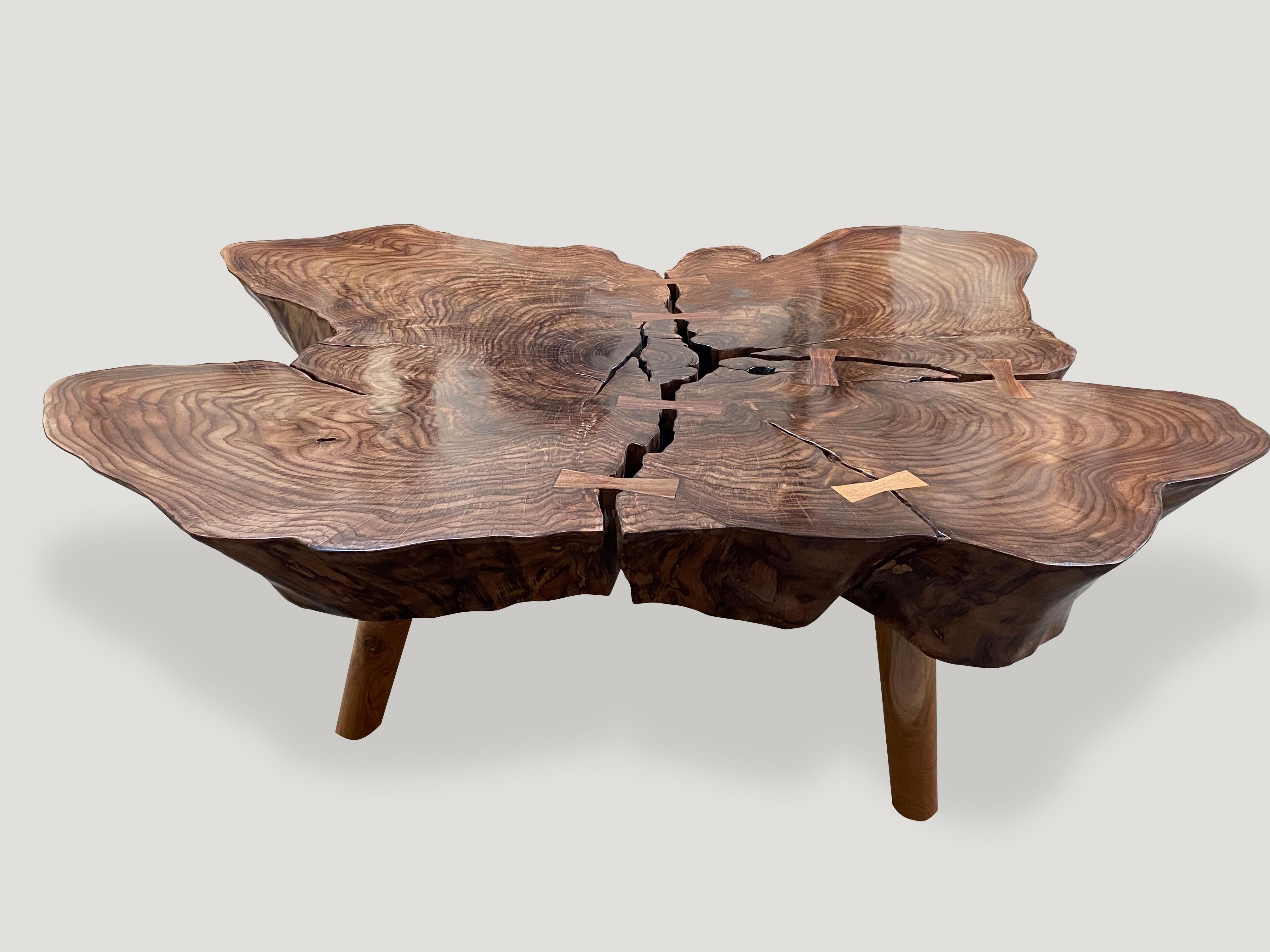 Impressionnante table basse en bois de rose recyclé. Nous avons poli le plateau avec une huile naturelle pour faire ressortir les magnifiques veines du bois sur ce plateau en forme de papillon. Flottant sur des pieds en teck de style milieu de