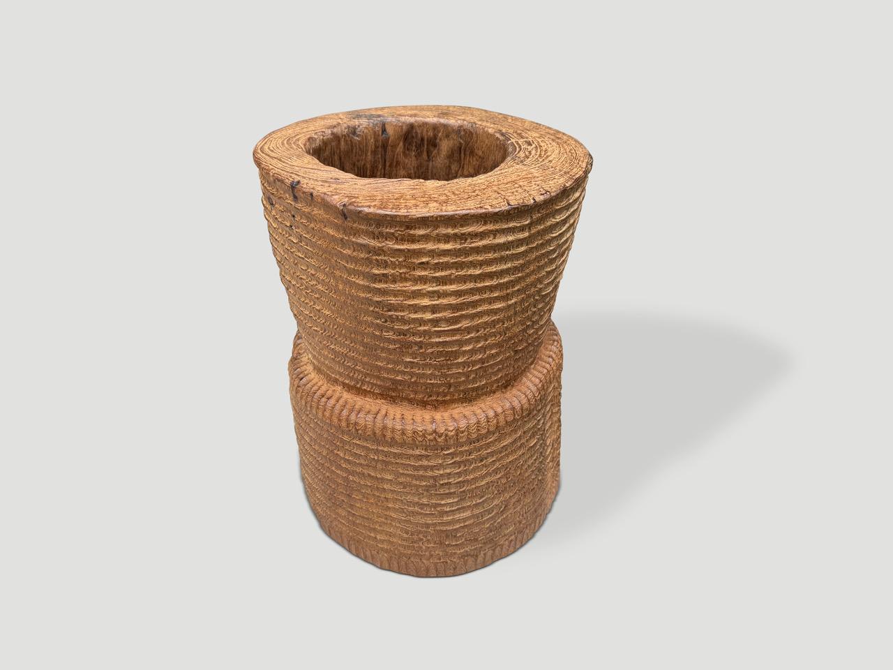 A beautiful ancient mortar originally used to pound rice from Sumatra, is repurposed as an art piece, container or side table depending on which side it is placed. Our master carver added the minimalist carving whilst respecting the organic wood.