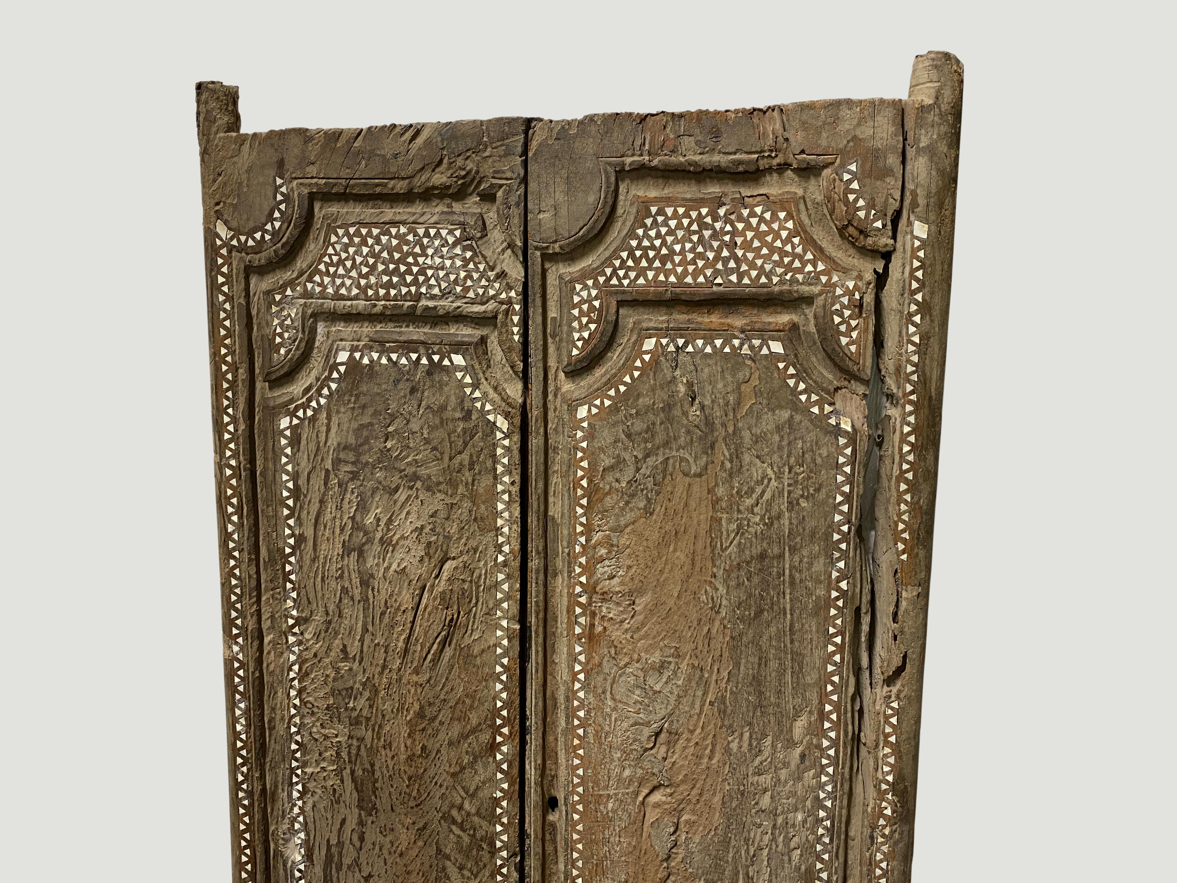 Ancient temple door that celebrates cracks and crevices found in aged teak wood. We added the shell inlay by hand. Great as a headboard, coffee table or simply as a piece of art. We currently have a large collection of temple doors available. All