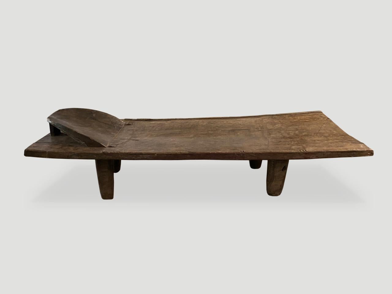 Hand carved by the Senufo tribes from a single block of iroko wood, native to the west coast of Africa. The wood is tough, dense and very durable. Shown with cone style legs and a raised headrest. Originally used as a bed, that can now be used as a