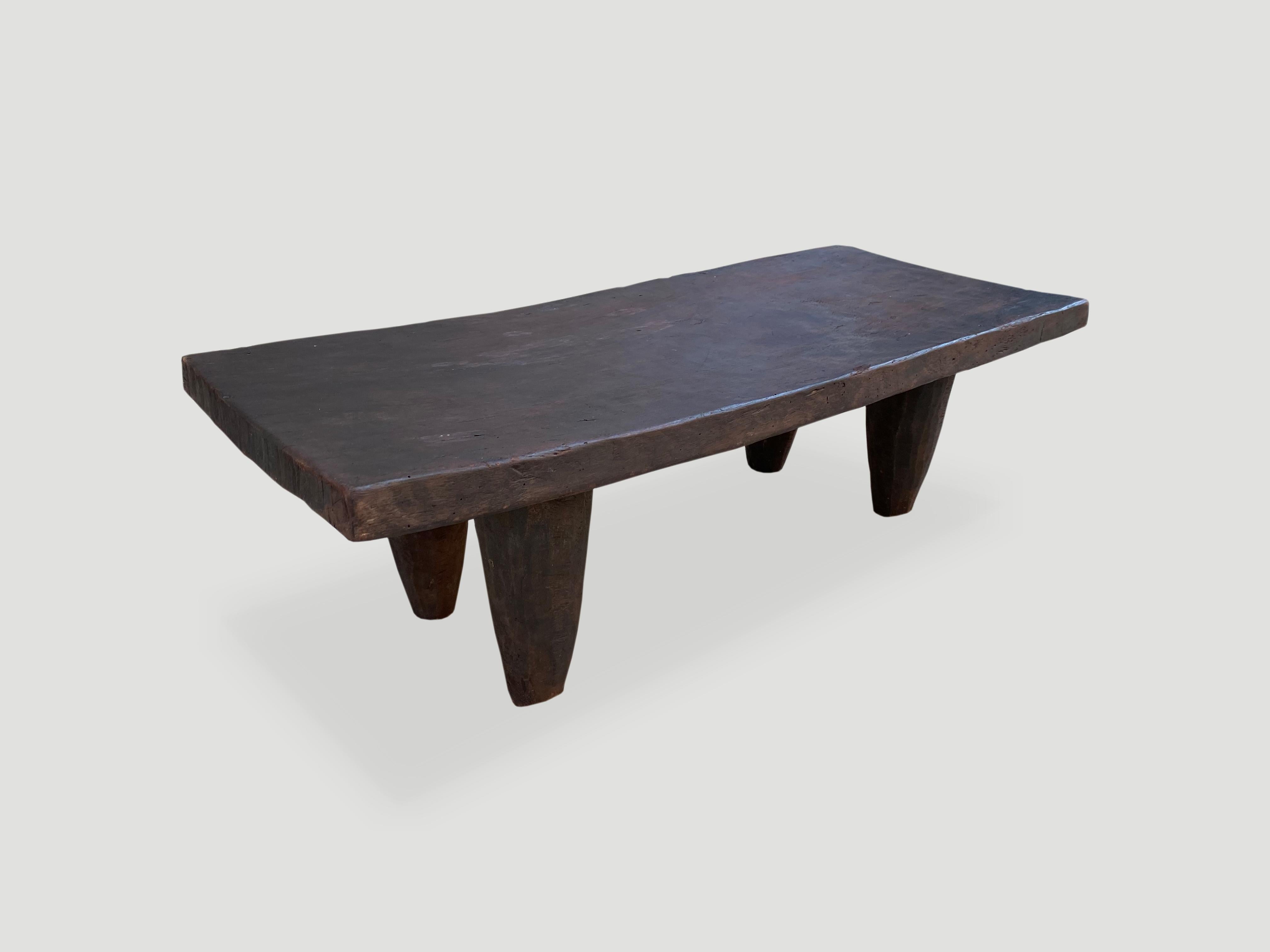 Antique coffee table or bench hand carved by the Senufo tribes from a single block of iroko wood, native to the west coast of Africa. The wood is tough, dense and very durable. This one is unusually long and shown with cone style legs. We only