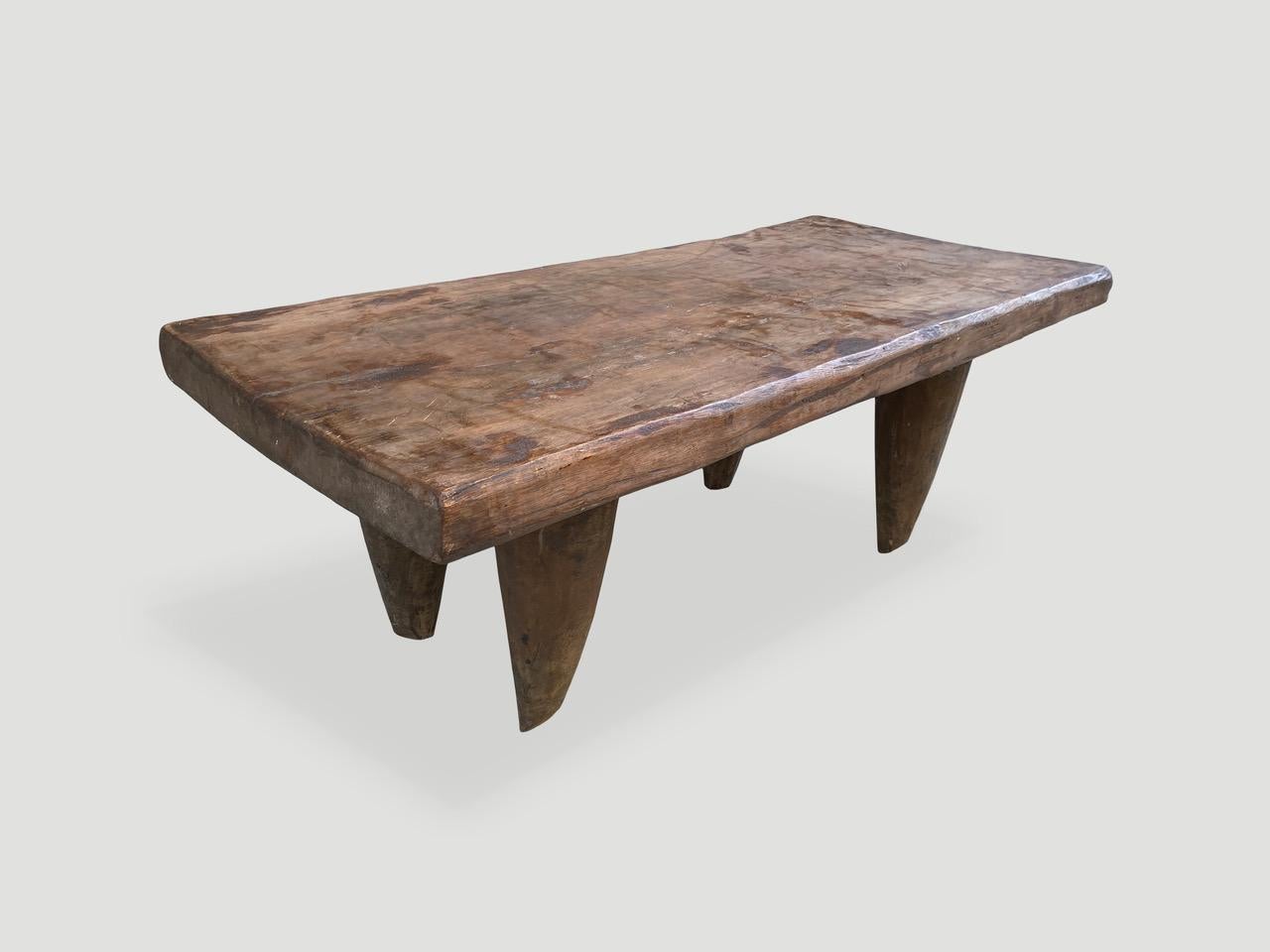 Antique coffee table or bench hand carved by the Senufo tribes from a single block of iroko wood, native to the west coast of Africa. The wood is tough, dense and very durable. Shown with cone style legs and with a two inch thick top. An unusual