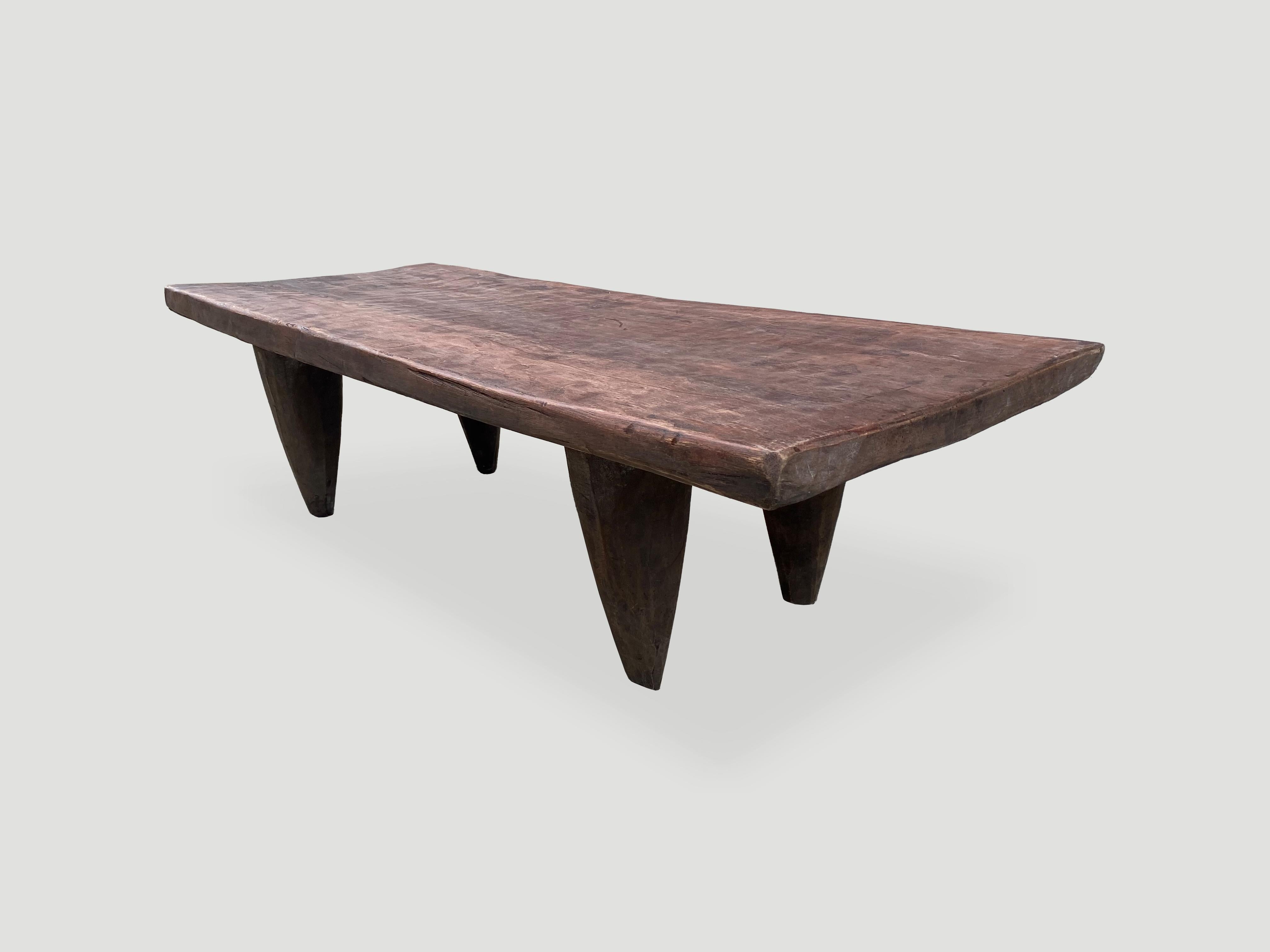 Antique coffee table or bench hand carved by the Senufo tribes from a single block of iroko wood, native to the west coast of Africa. The wood is tough, dense and very durable. Shown with cone style legs and with a two inch thick top. An unusual