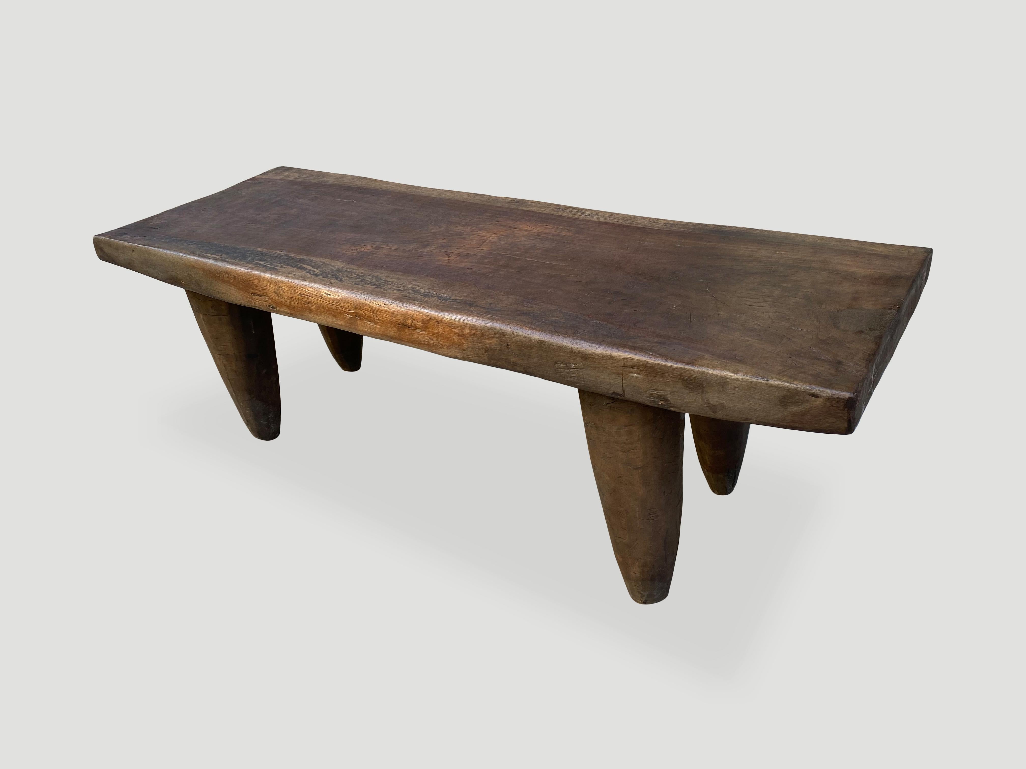Antique coffee table or bench hand carved by the Senufo tribes from a single block of iroko wood, native to the west coast of Africa. The wood is tough, dense and very durable. Shown with cone style legs and with a two inch thick top. Beautiful tone