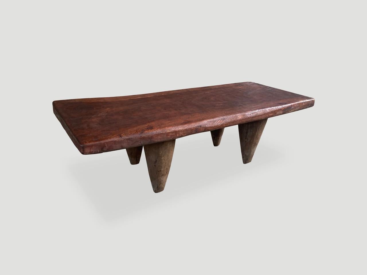 Antique coffee table or bench hand carved by the Senufo tribes from a single block of iroko wood, native to the west coast of Africa. The wood is tough, dense and very durable. Shown with cone style legs and with a two inch thick top. We only source