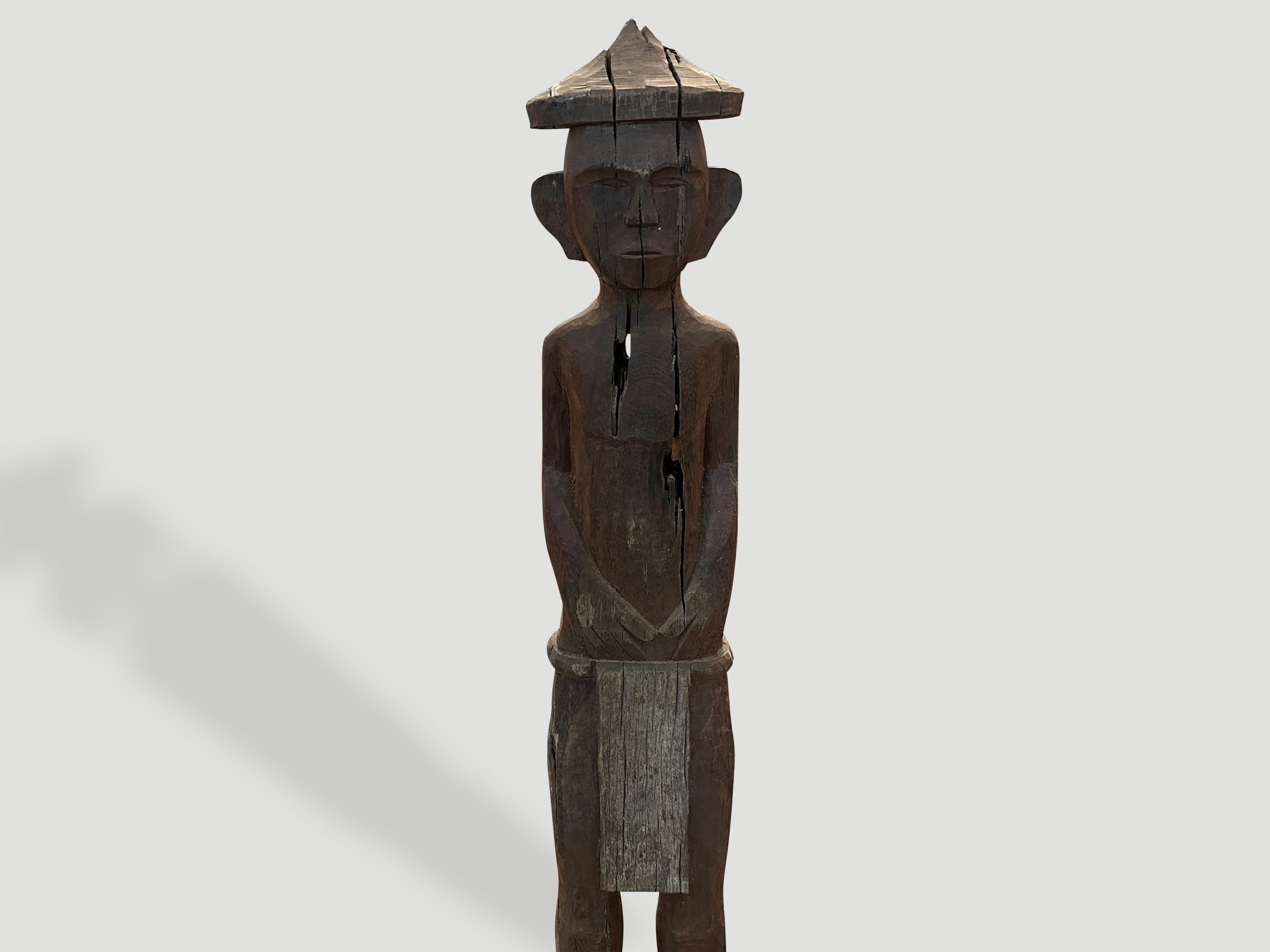 Antique male statue hand carved from a single wood log from West Borneo. Originally used to protect the home from evil spirits. The wood base was placed into the ground in front of the house as a guardian. We added an 8” x 8” modern metal black