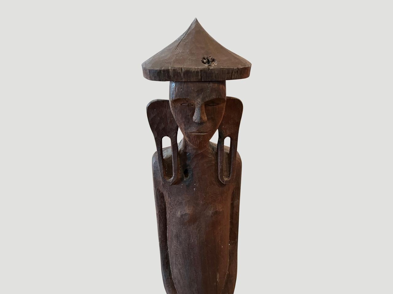 Antique male statue hand carved from a single wood log from West Borneo. Originally used to protect the home from evil spirits. The wood base was placed into the ground in front of the house as a guardian. We added an 8” x 8” modern metal black
