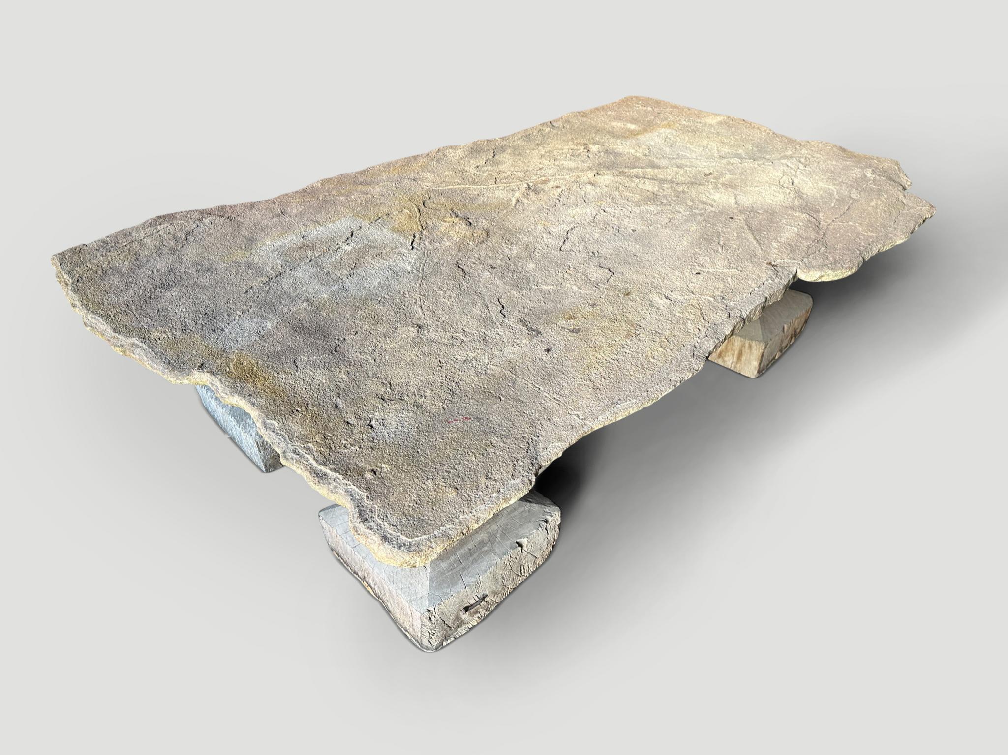 Beautiful antique Sumba stone live edge coffee table. This one of a kind slab rests on four hand carved teak century old  bases, original used as a base for a column. Fabulous textures and tones on this stunning four inch slab. Rare.

This coffee