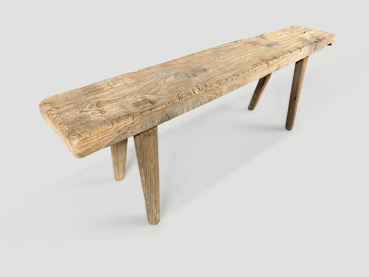 Eine einzelne dicke antike Holzplatte mit schönem Charakter. Wir haben glatte, minimalistische Teakholzbeine hinzugefügt, um diese schöne Bank herzustellen, und sie mit unserer geheimen Zutat veredelt, wodurch die einzigartige Holzmaserung zum