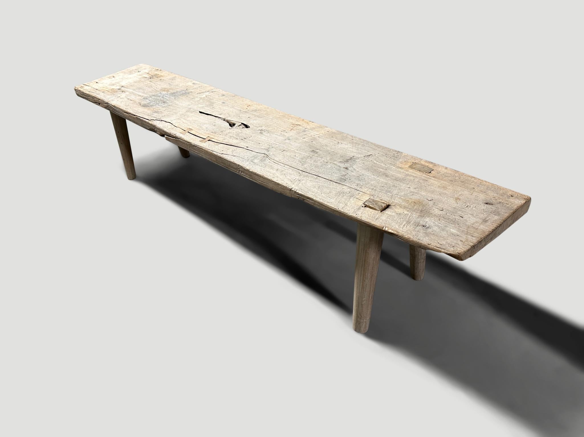 Antique Wabi Sabi bench with pale wood tones. A single wide aged teak slab celebrating the cracks and crevices and all the other marks that time and loving use have left behind. We added smooth teak minimalist legs and butterflies inlaid into the