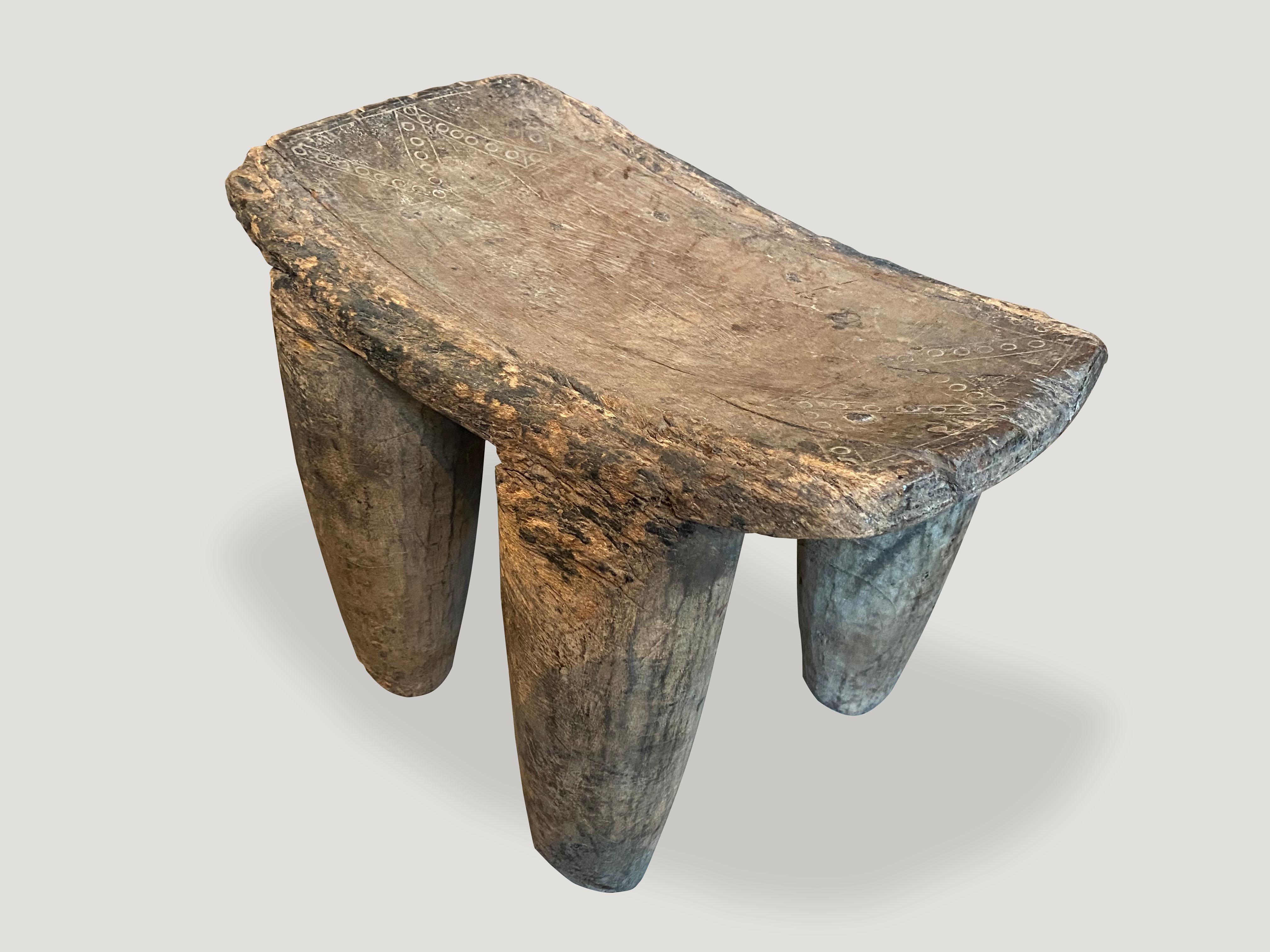 Stunning patina on this impressive African stool, hand carved from a single block of wood with beautiful markings celebrating the cracks and crevices that time and loving use have left behind. This almost feels like a fossilized piece of art. Great