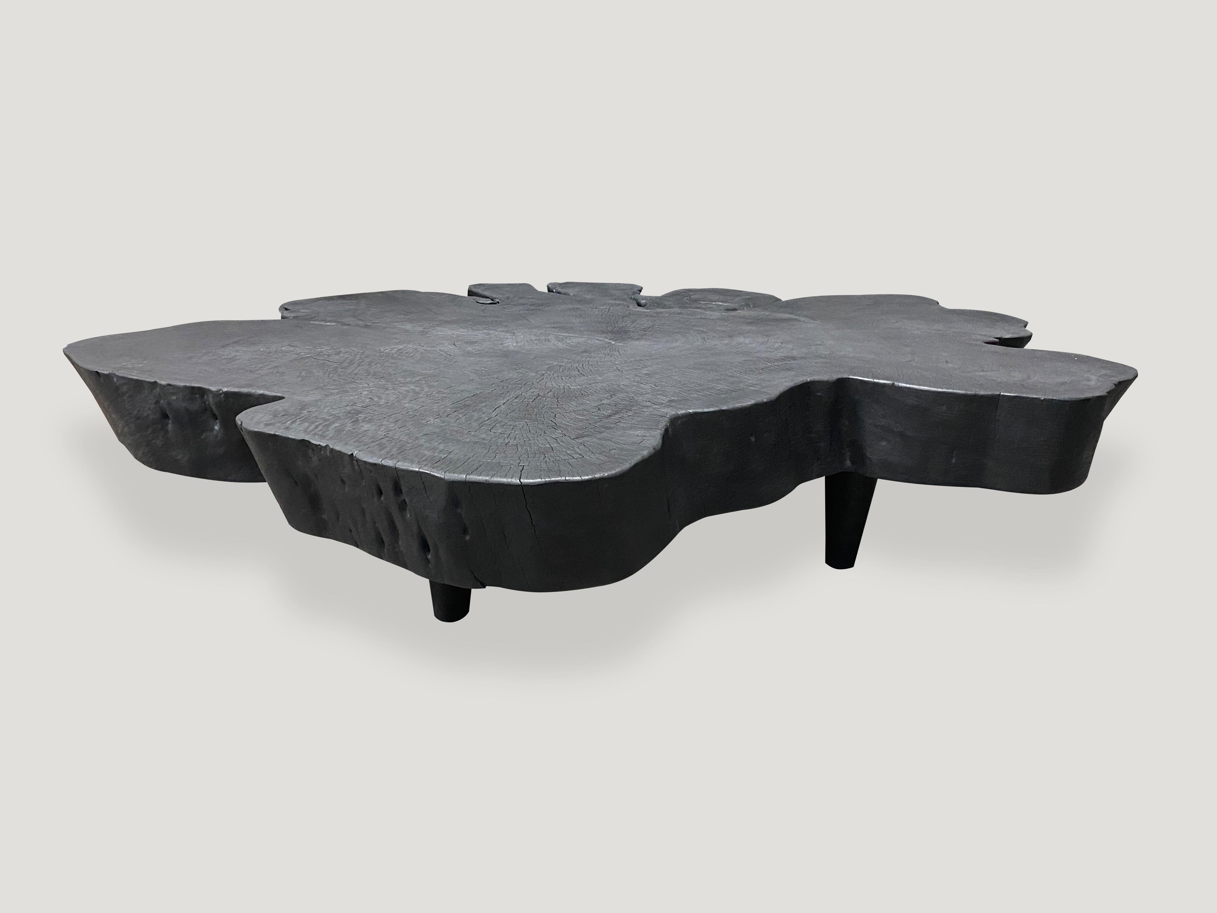 Impressive reclaimed mango wood coffee table made from a six inch single slab. The top floats off the floor on mid century style cone shaped legs. Charred, sanded and sealed exposing the beautiful grain of the wood. Custom finishes available. All