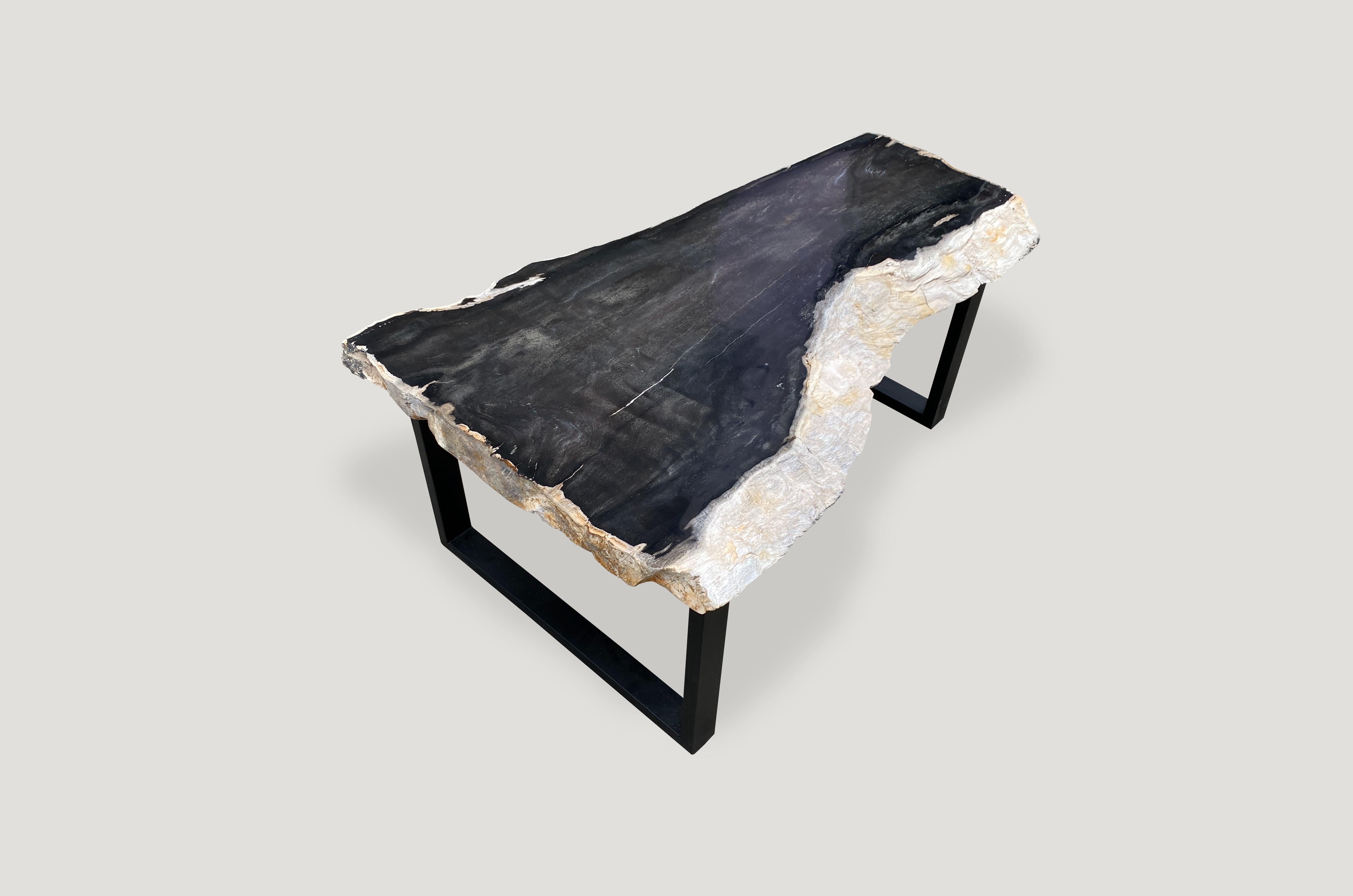 Rare, hard to find black and white tones on this super smooth, high quality petrified wood coffee table. We polished the two inch top smooth like glass and left the white sides raw in contrast. Set on a black metal base. The last two images are