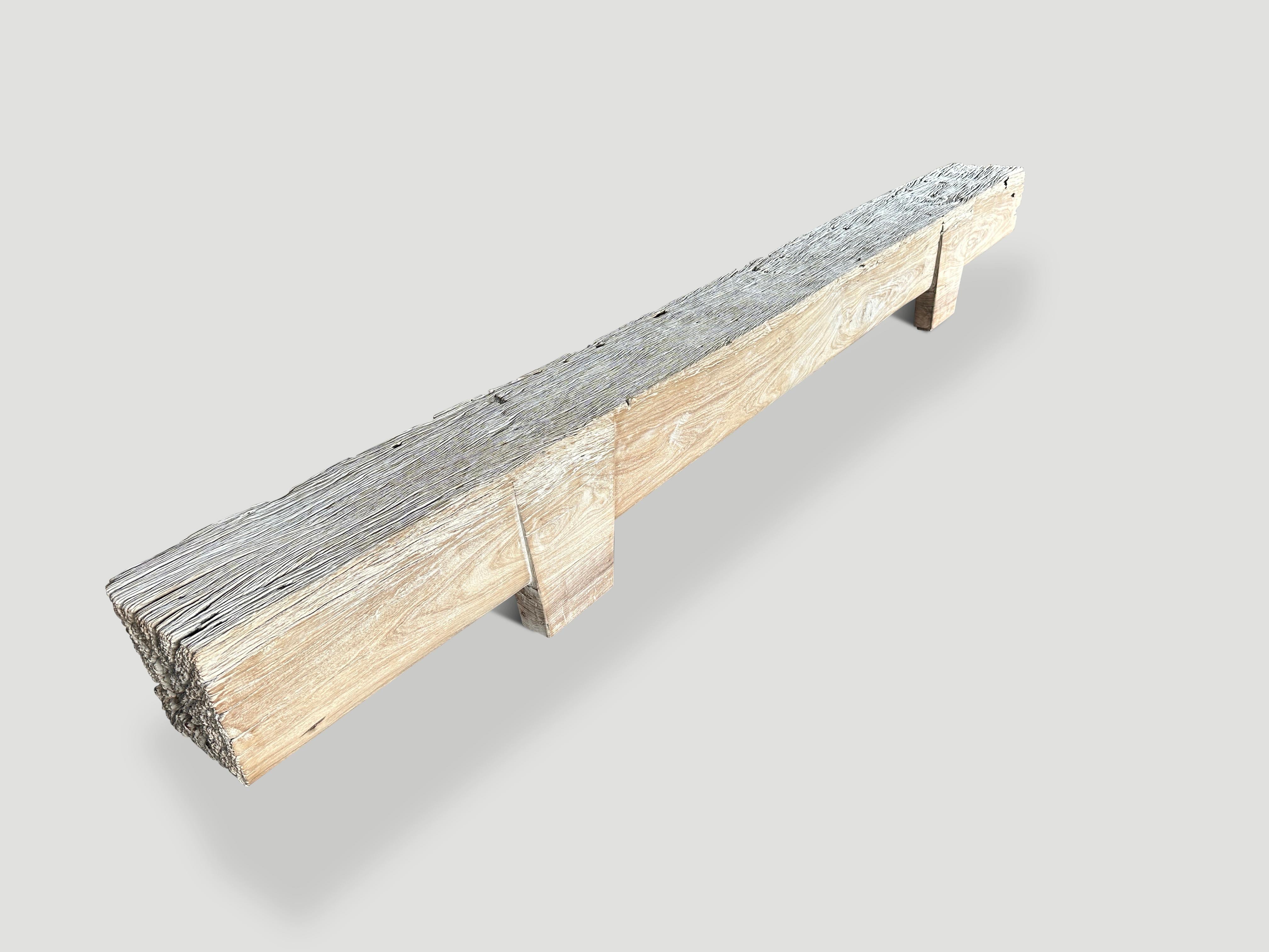 Impressive reclaimed bleached teak log bench. The legs are cut into this super rare long bench. The log is ten inches thick and floats seven inches off the floor on minimalist hand carved legs. We added a bleach and light white wash revealing the