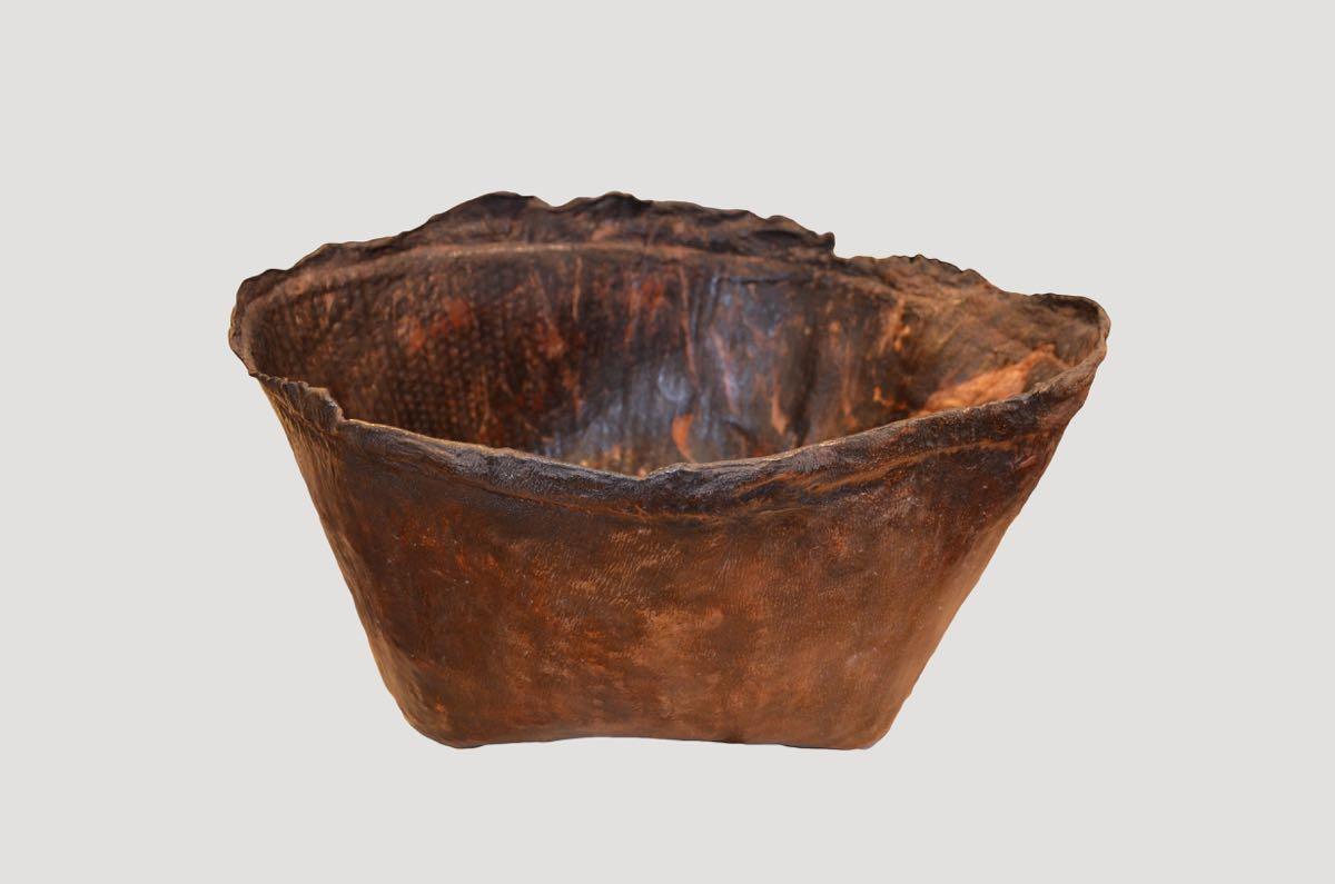 Antique container from Borneo made from aged buffalo hide and formed to produce a bowl. Beautiful dark brown patina and natural organic rim. Great for holding magazines, towels, firewood, etc.

This container was sourced in the spirit of