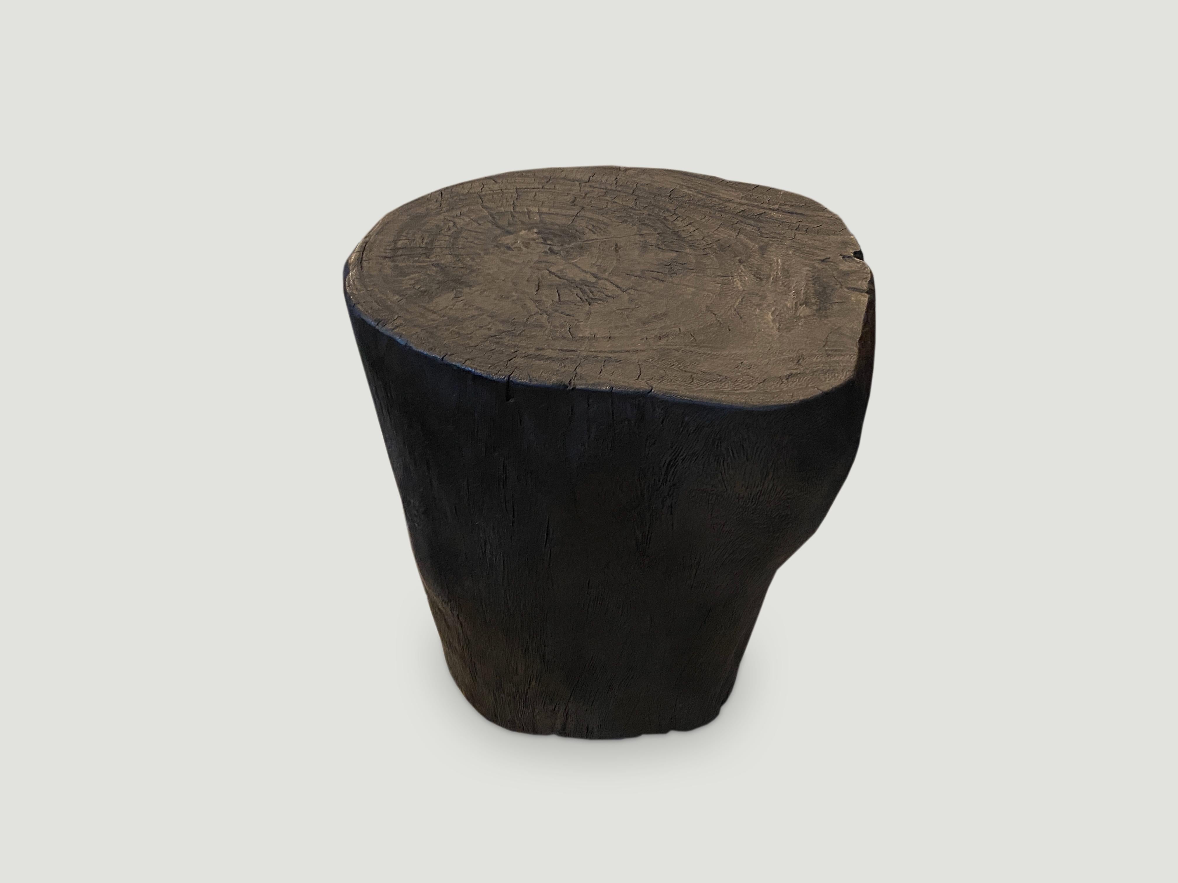 Hand carved solid reclaimed suar wood sculptural side table. Burnt, sanded and sealed whilst respecting the natural organic wood and shape. We have a collection. All unique. The price and size reflects the one shown. 

The Triple Burnt collection