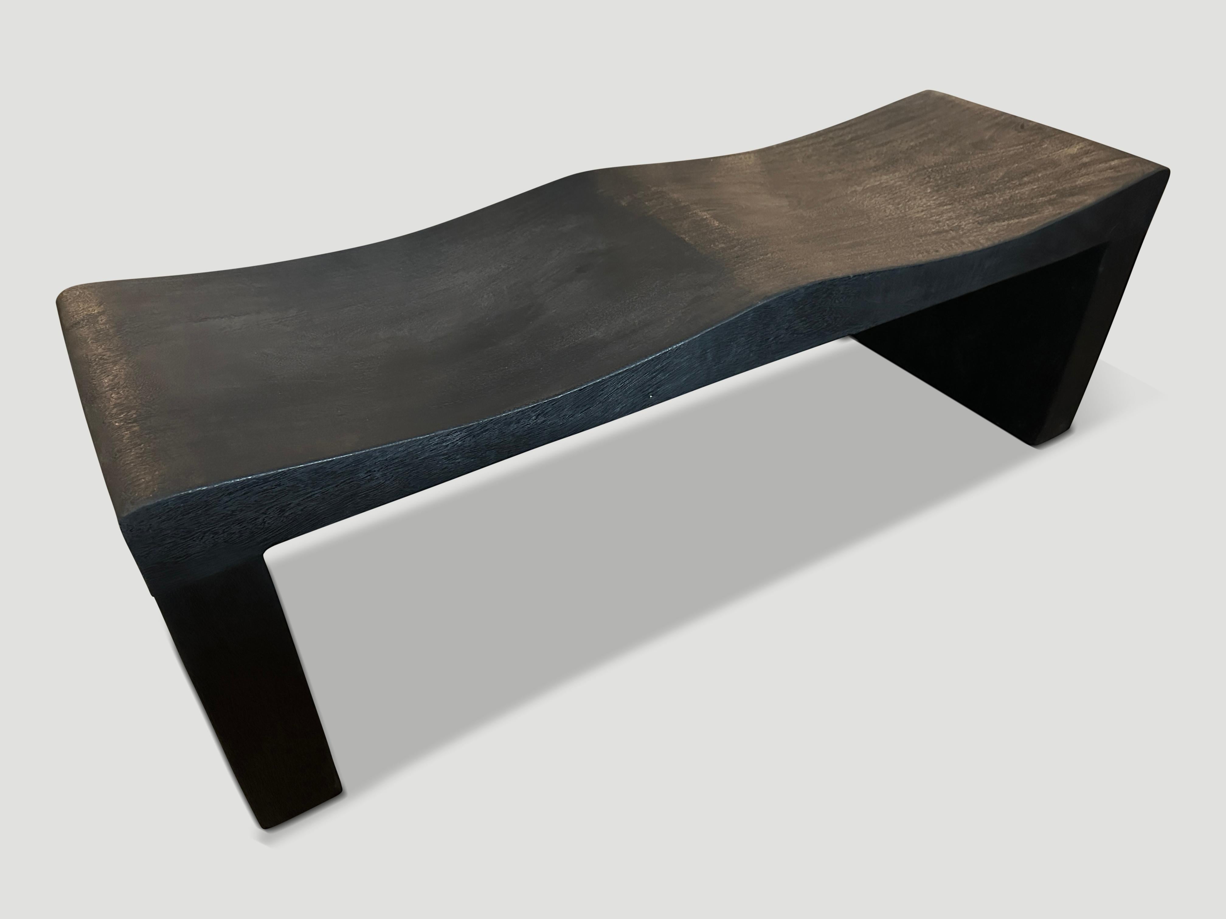 The teak wave bench represents a sleek, modern aesthetic, designed to provide comfort and durability. Solid reclaimed teak wood is hand carved into a wave design. Charred, sanded and sealed revealing the beautiful wood grain. Custom stains and