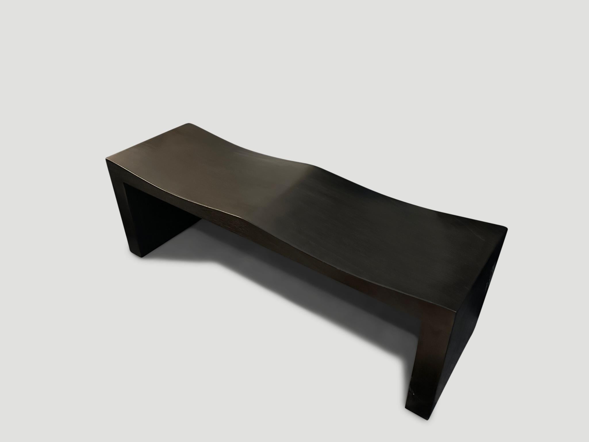 The teak wave bench represents a sleek, modern aesthetic, designed to provide comfort and durability. Solid reclaimed teak wood is hand carved into a wave design. Charred, sanded and sealed revealing the beautiful wood grain. Shown with a smooth