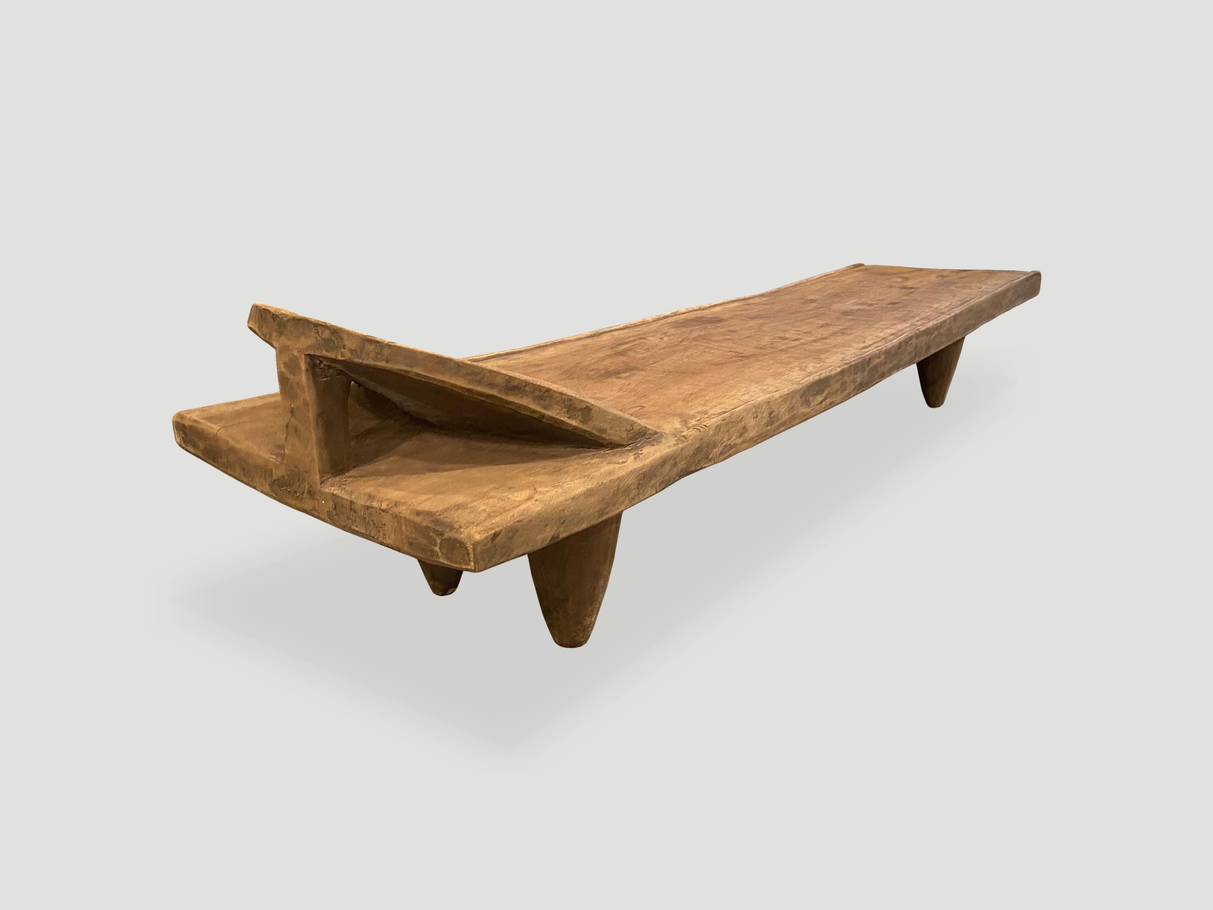 Hand carved by the Senufo tribes from a single block of iroko wood, native to the west coast of Africa. The wood is tough, dense and very durable. Shown with cone style legs and a raised six inch headrest. Originally used as a bed, that can now be
