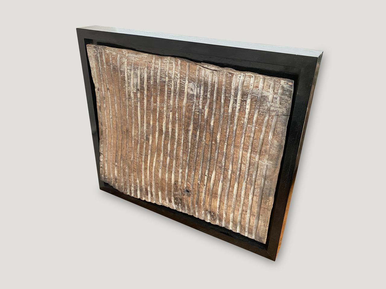Antique hand carved panel from Toraja. Framed in a Minimalist black teak wood shadow box. This carving symbolizes the protection of the home. Great art piece.

This antique carving was sourced in the spirit of wabi-sabi, a Japanese philosophy that