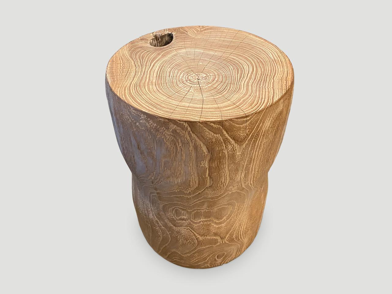 Hand carved cerused teak side table or stool with a subtle smooth hourglass shape that celebrates the cracks and crevices found in reclaimed teak. This style works well in a variety of interior settings such as seating or side tables, as shown in