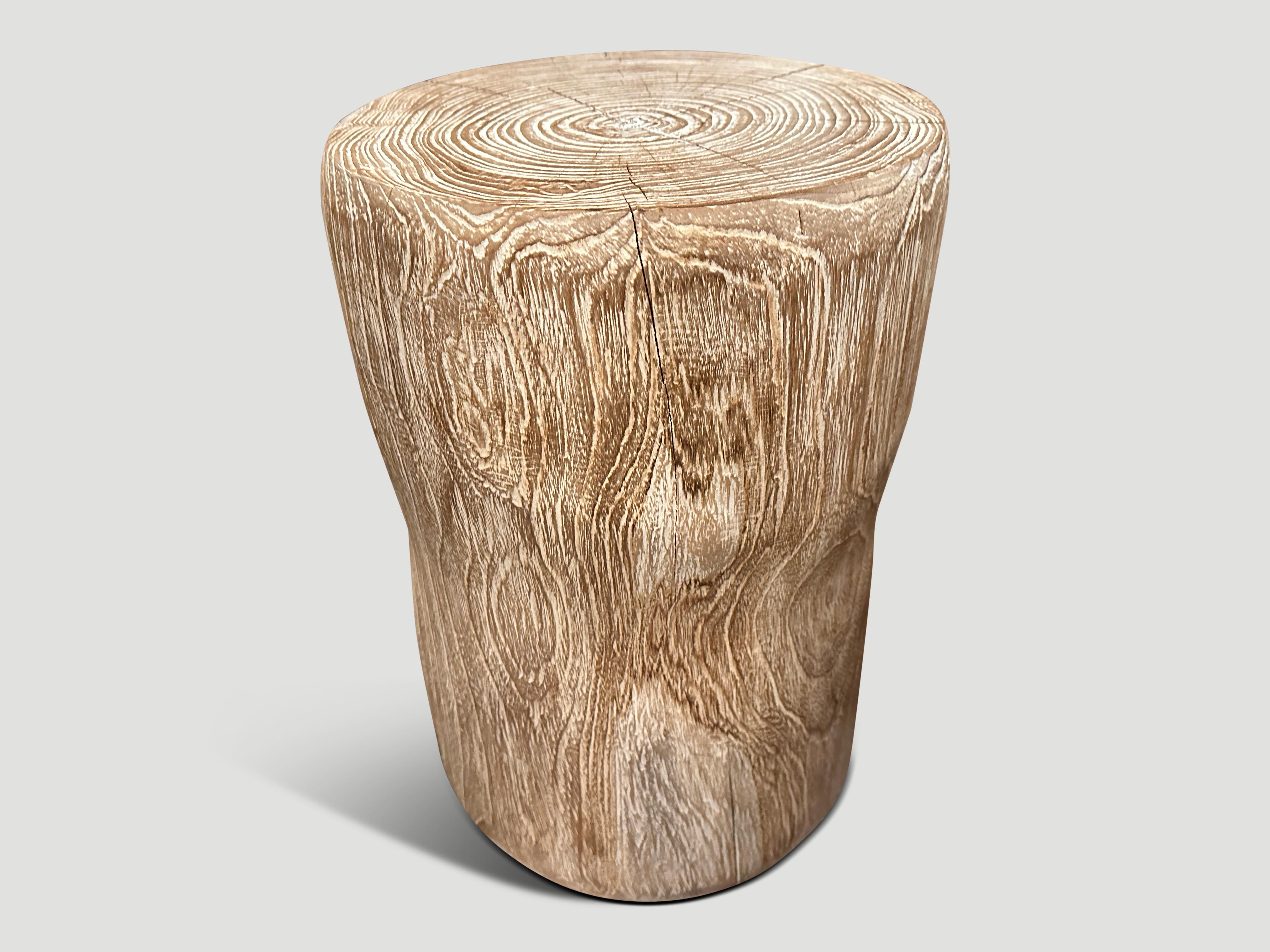 Hand carved cerused teak side table or stool with a subtle hourglass shape. Celebrating the cracks and crevices found in reclaimed teak wood. This style works well in a variety of settings such as seating or side tables, as shown in the bottom image