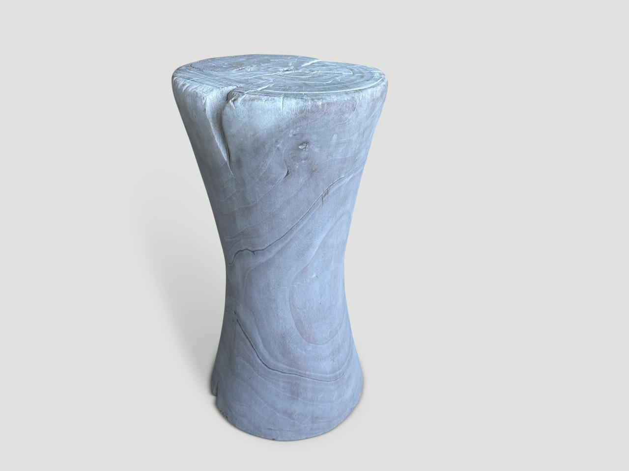 Sculptural hourglass side table or stool. Bleached and then finished with a light white wash revealing the beautiful grain on this century old teak wood. It’s all in the details. Pair available. The price and images reflect the one shown.

The St.