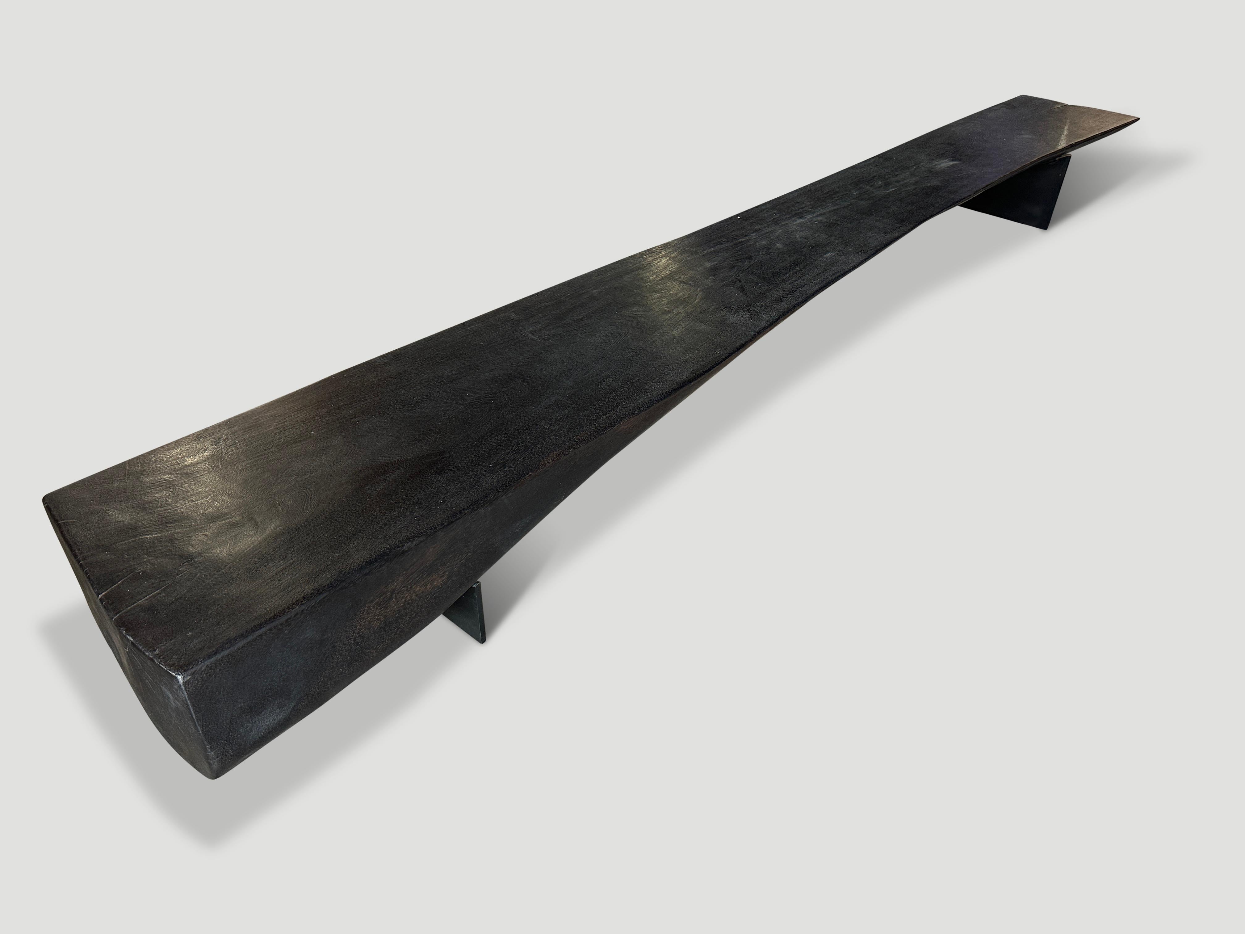 A beautiful suar wood reclaimed log has been cut in half to produce this dramatic long bench with a live edge from 20” to 15” wide. We added sleek minimalist steel legs in contrast to this ten inch thick log. Lightly charred revealing the unique