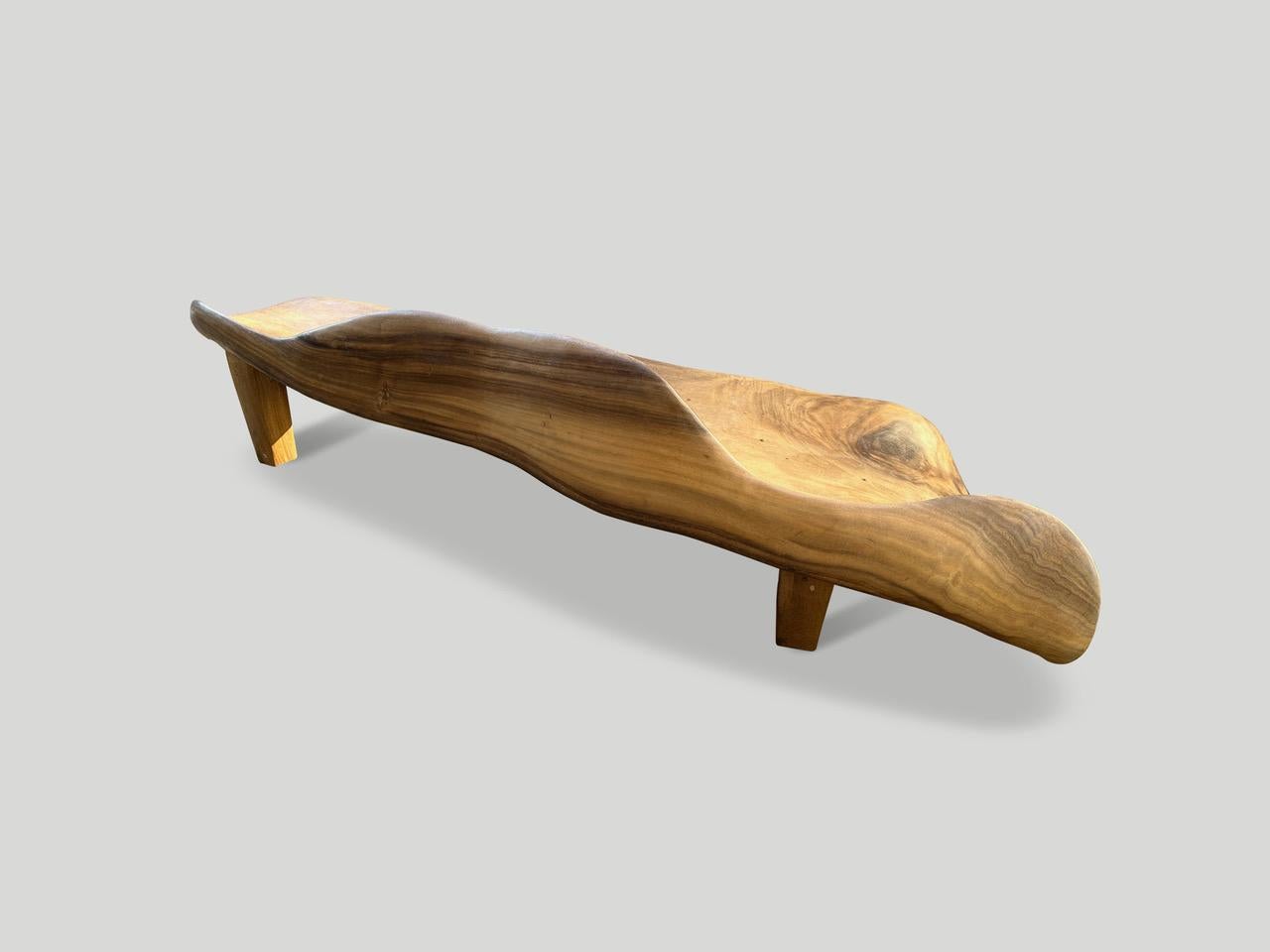 Impressive one of a kind bench with the seat and back rest hand carved seamlessly from a single piece of suar wood. We added minimalist legs and finished this rare piece with a natural oil revealing the beautiful wood grain. Both usable and