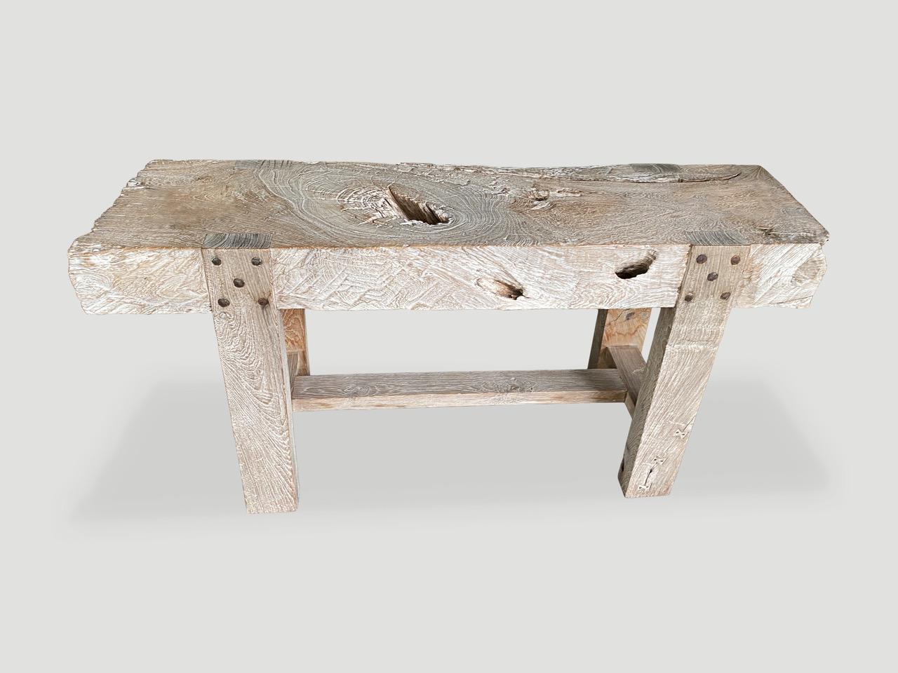 Magnifique table console en teck vieilli avec un plateau en dalles de 15 cm d'épaisseur. La quincaillerie d'origine et les détails des papillons incrustés sur le pied de cette superbe pièce. Nous avons ajouté une finition céruse pour révéler le