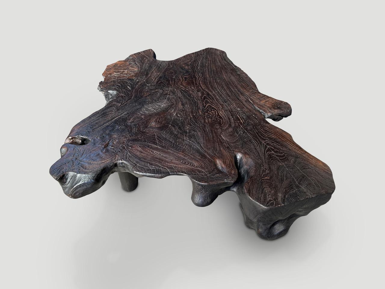 Natural organic formed reclaimed teak root coffee table. We added two cone style legs to level out this otherwise single slab. Charred to a rich chocolate brown. Finally we rubbed the top with a wire brush revealing the beautiful wood grain. It’s