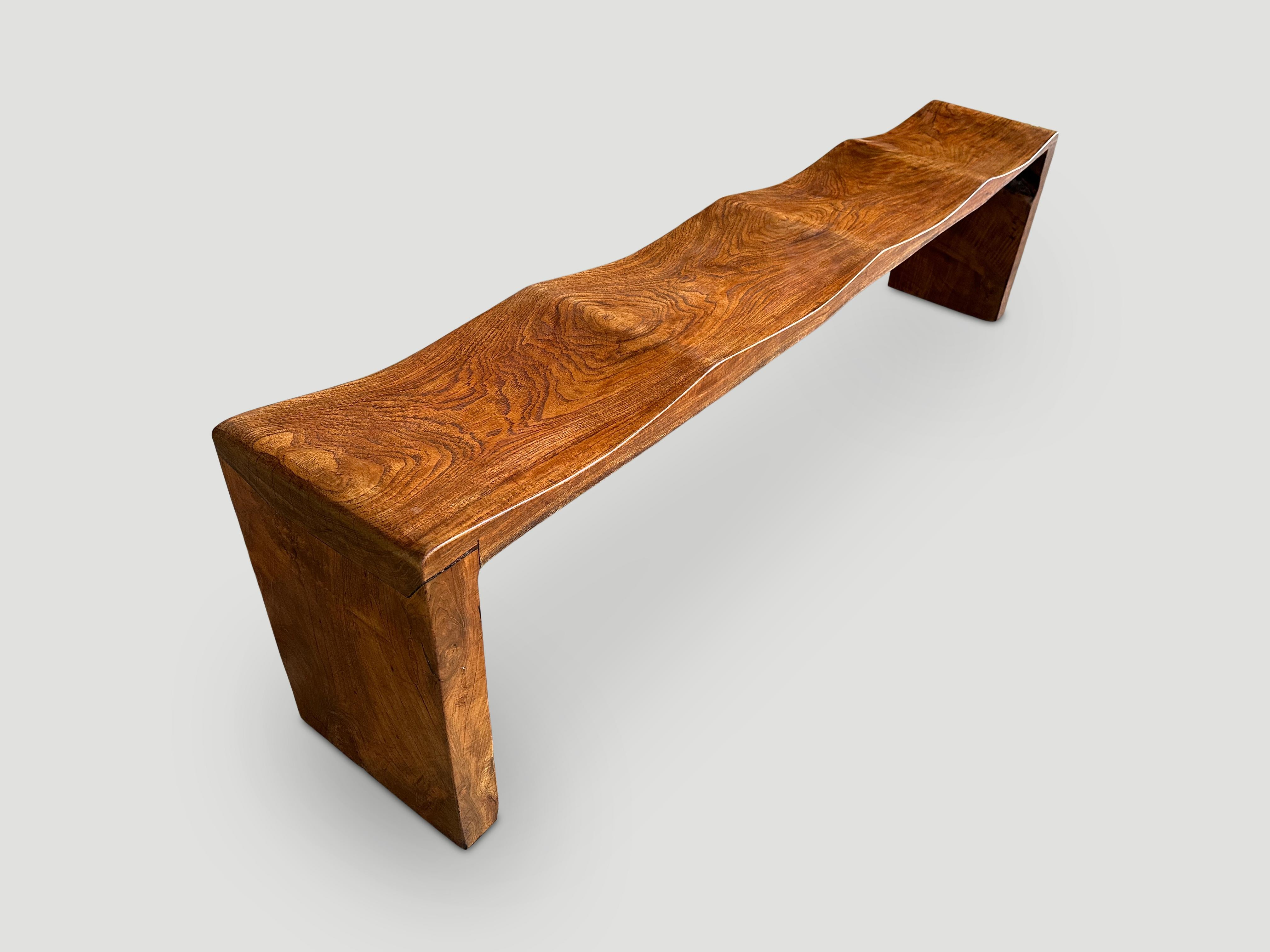 A solid single slab of reclaimed teak wood is hand carved into this stunning design with four deep waves. Finished with a natural oil revealing the beautiful wood grain. 

This bench was hand made in the spirit of Wabi-Sabi, a Japanese philosophy