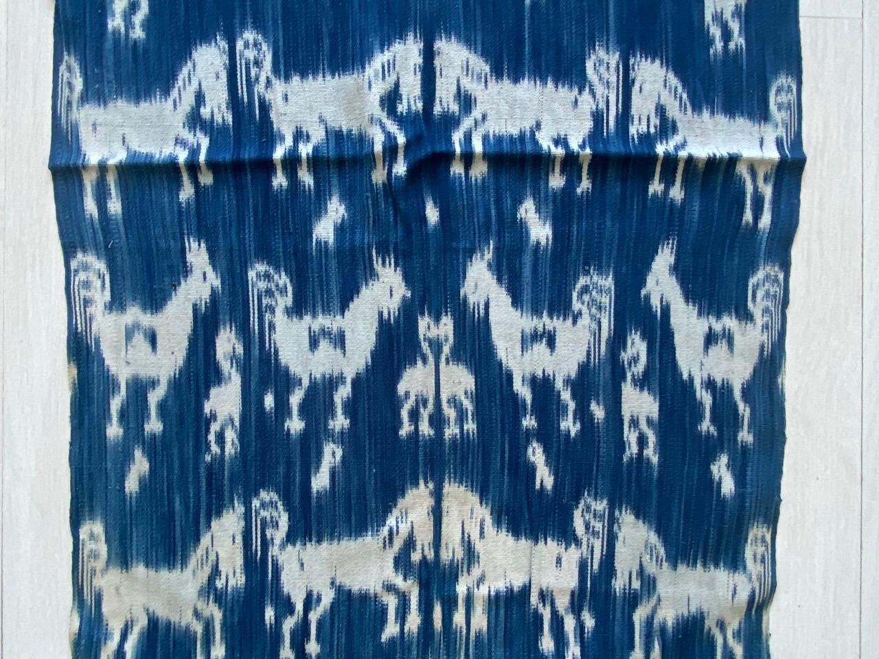 Antikes indigoblaues und weißes Textil aus Sumba. Die perfekte Größe, um sie als Schal zu tragen. Mythische Figuren, Pferde und Vögel vermischen sich in diesem grafischen Textil. Ikat ist eine alte Technik, mit der Textilien mit Mustern versehen