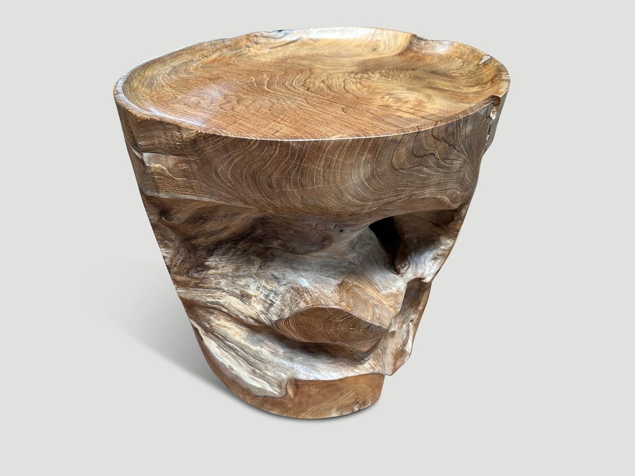 Mesa auxiliar de raíz de teca recuperada con forma orgánica natural. Tallamos a mano la parte superior en forma de bandeja y pulimos la teca envejecida con un aceite natural que revela la hermosa veta de la madera. Las secciones interiores se lijan