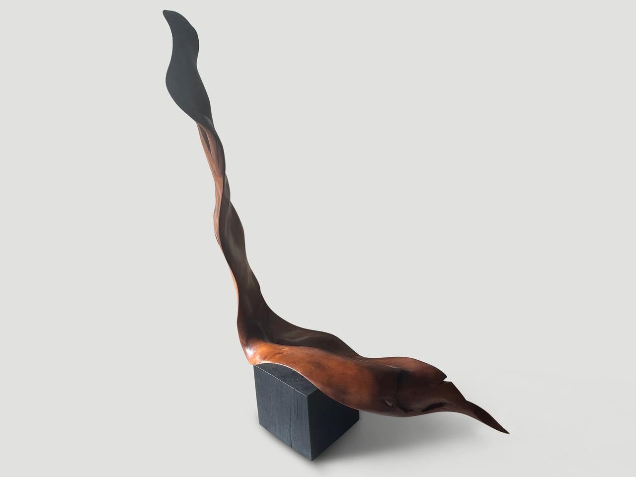 A beautiful thick piece of mahogany wood is set upon a minimalist charred cube. A sculptural chair or a one of a kind art piece. Full dimensions; 64″ high x seat 18-14″ high x 43″ wide. Polished with a natural oil revealing the stunning wood grain.