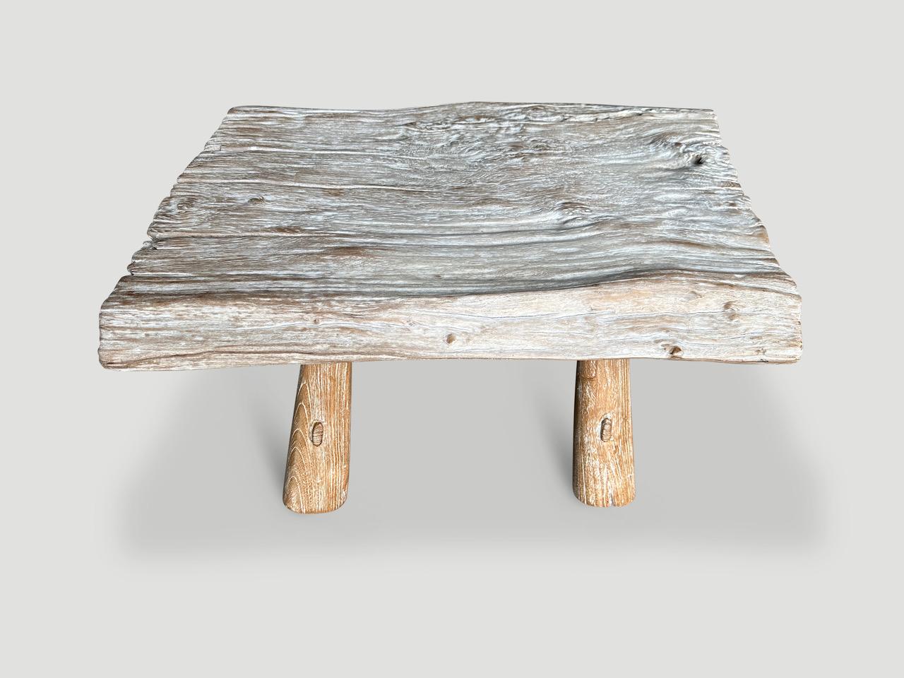 Impressionnante table basse en bois de teck centenaire avec de rares détails d'érosion aux extrémités. Nous avons ajouté une base de style mid century et fini le plateau avec une teinture laiteuse translucide révélant les magnifiques veines du bois.