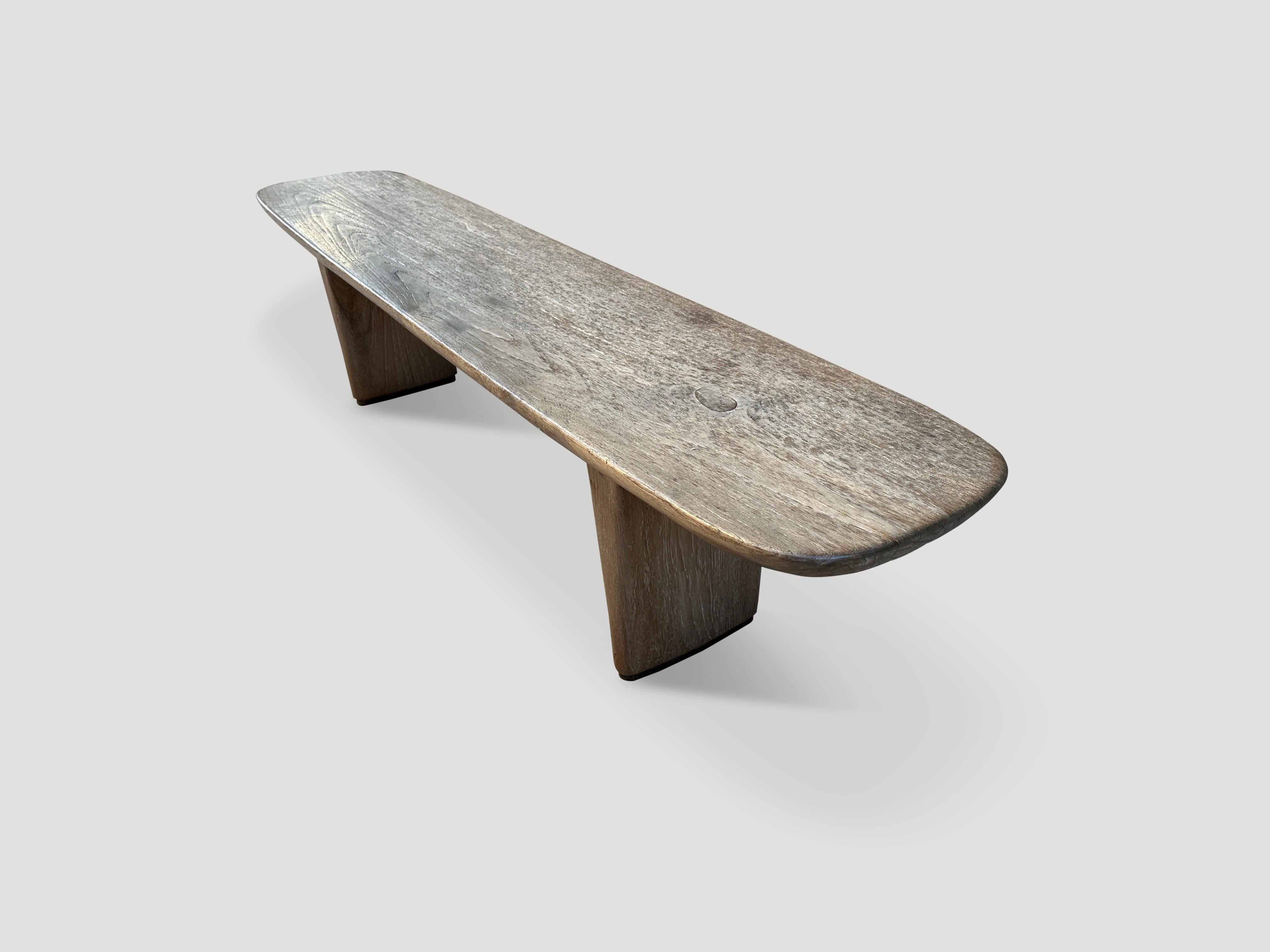 A beautiful single slab of teak wood taken from my finest collection is hand carved to produce this impressive bench. We added two minimalist tapered legs with a recess at the bottom in a darker tone. Finished with a translucent grey stain revealing