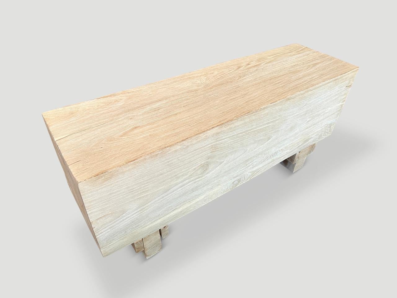 Reclaimed teak wood log bench floating six inches off the floor. Bleached to a bone finish and with an iron brush revealing the beautiful wood grain. It’s all in the details. Pair available. The price reflects the one shown. The two block bases can