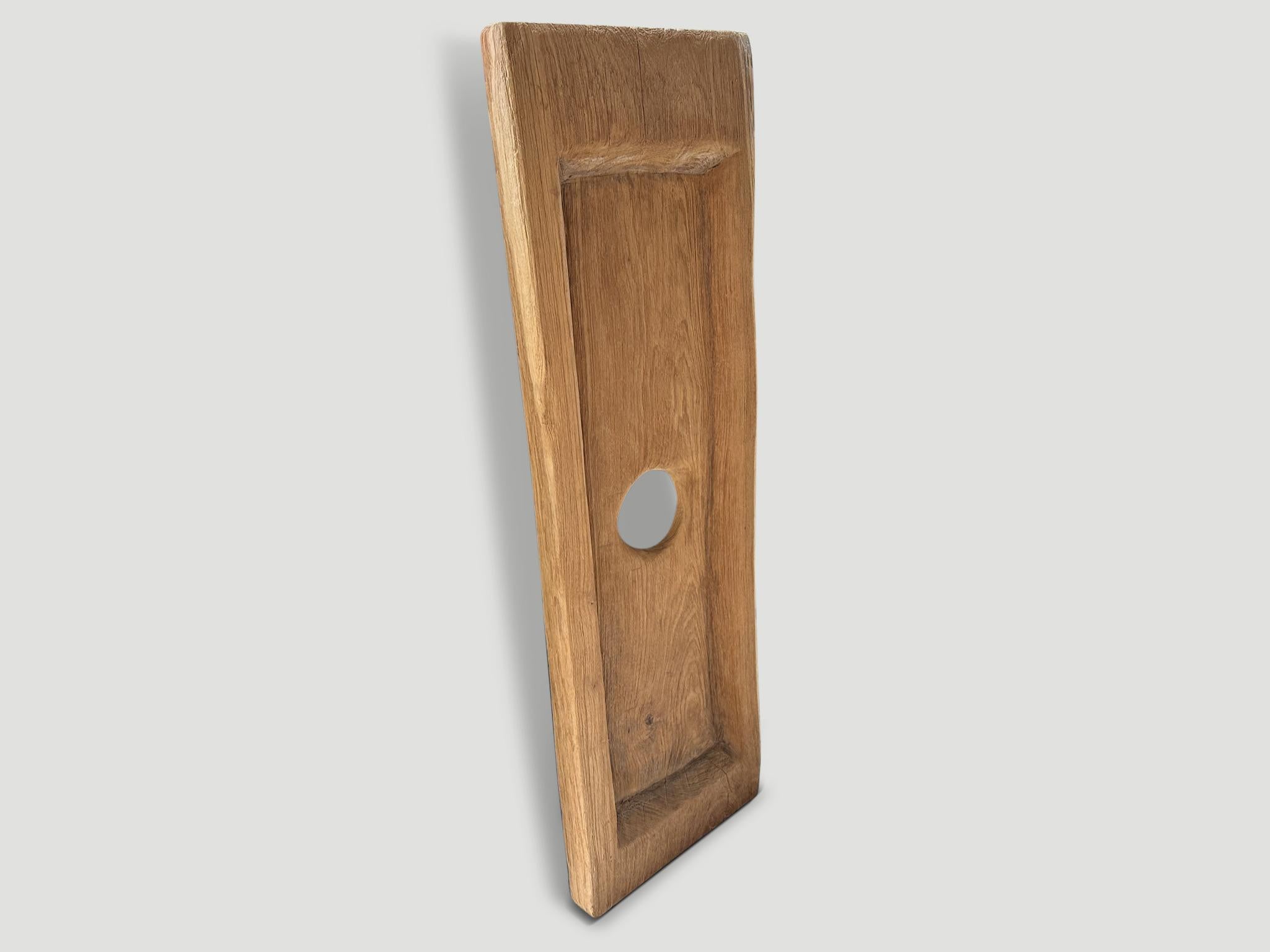 A single three inch thick old teak slab is hand carved into this minimalist wall hanging or tray. This can also be used as a console or coffee table top. Both usable and a piece of art.

This beautiful old teak panel was hand made in the spirit of